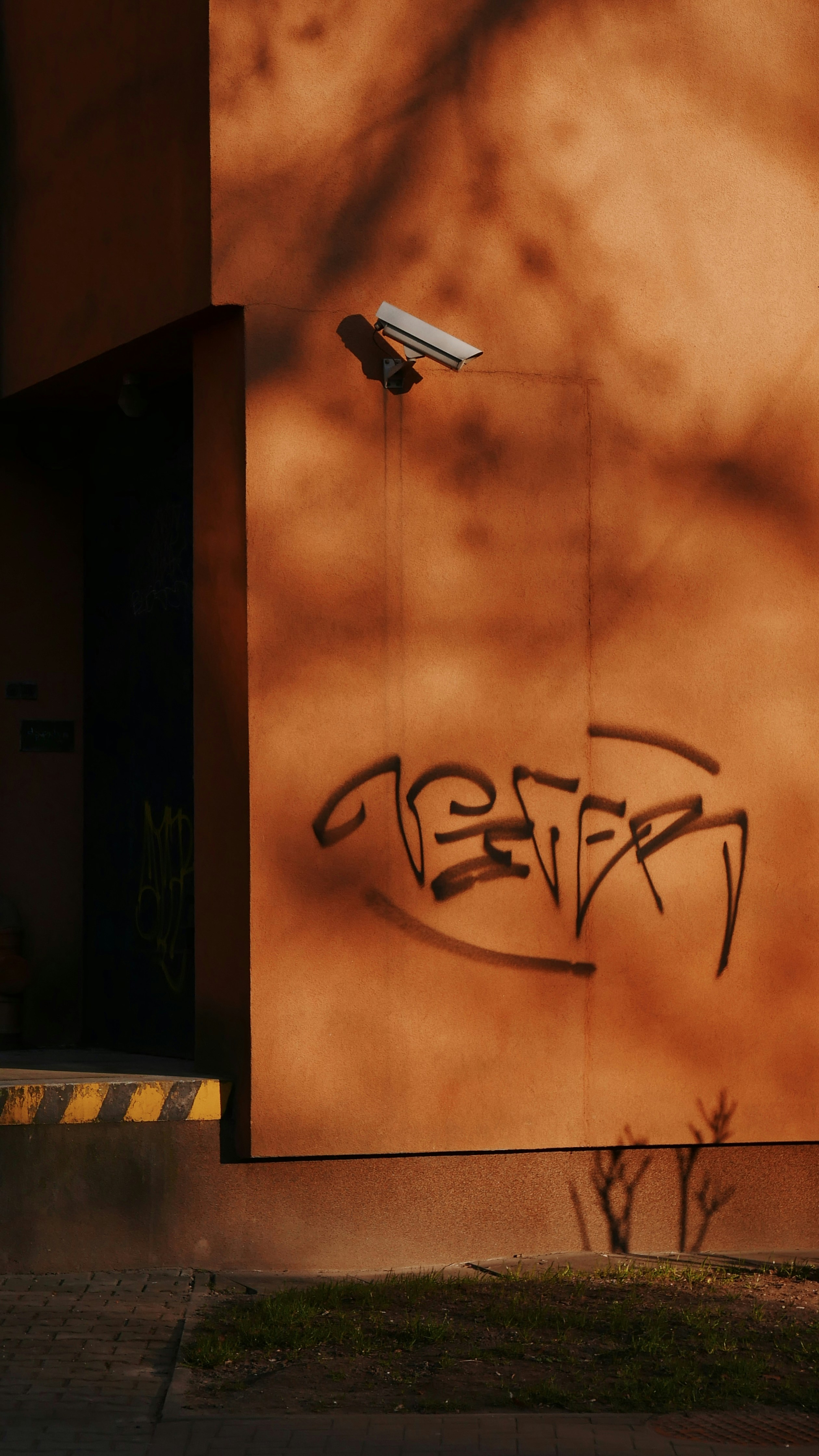 Überwachungskamera an der orangefarbenen Wand mit Graffiti