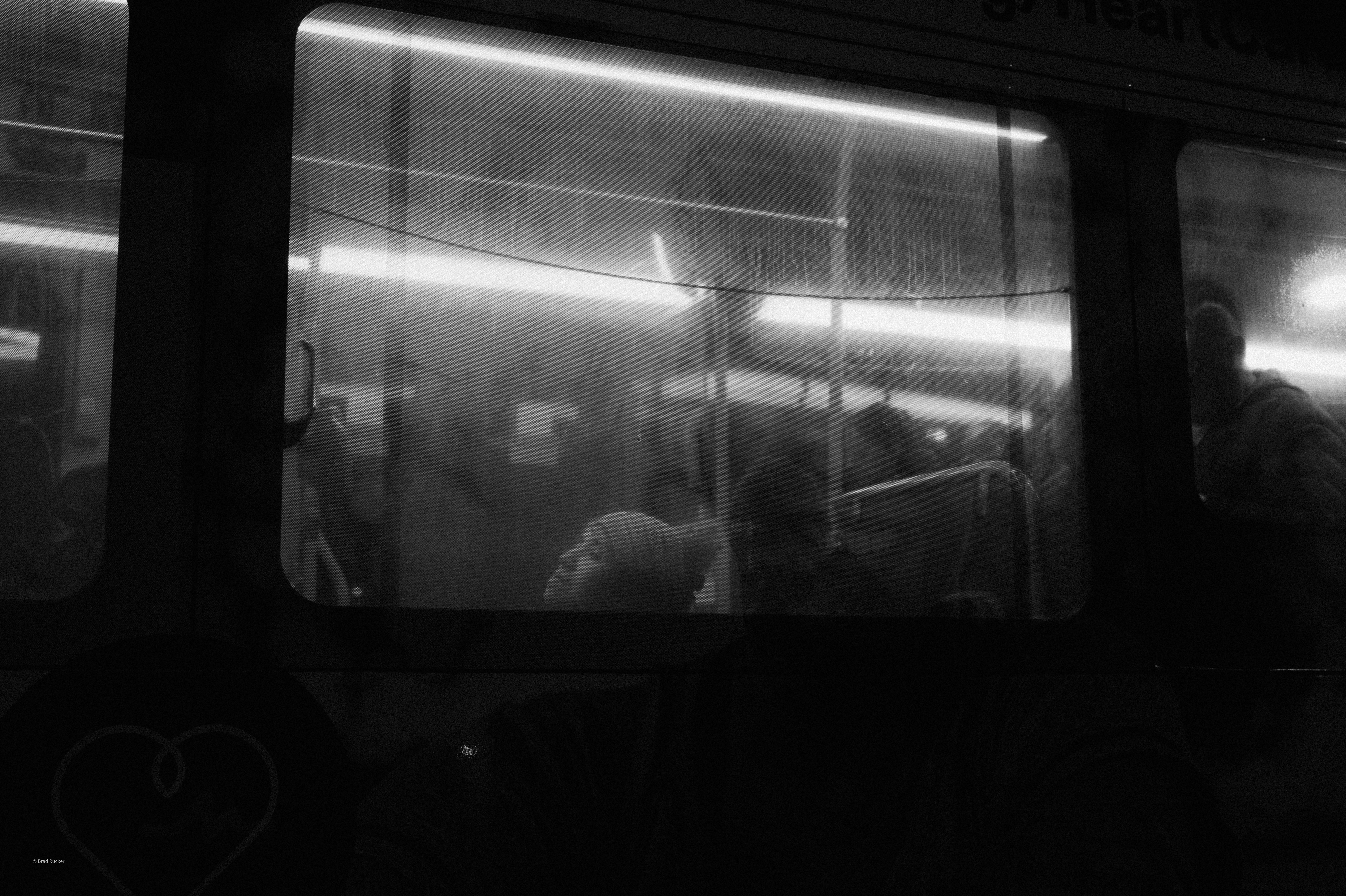 People silhouetted inside a dimly lit bus at night.