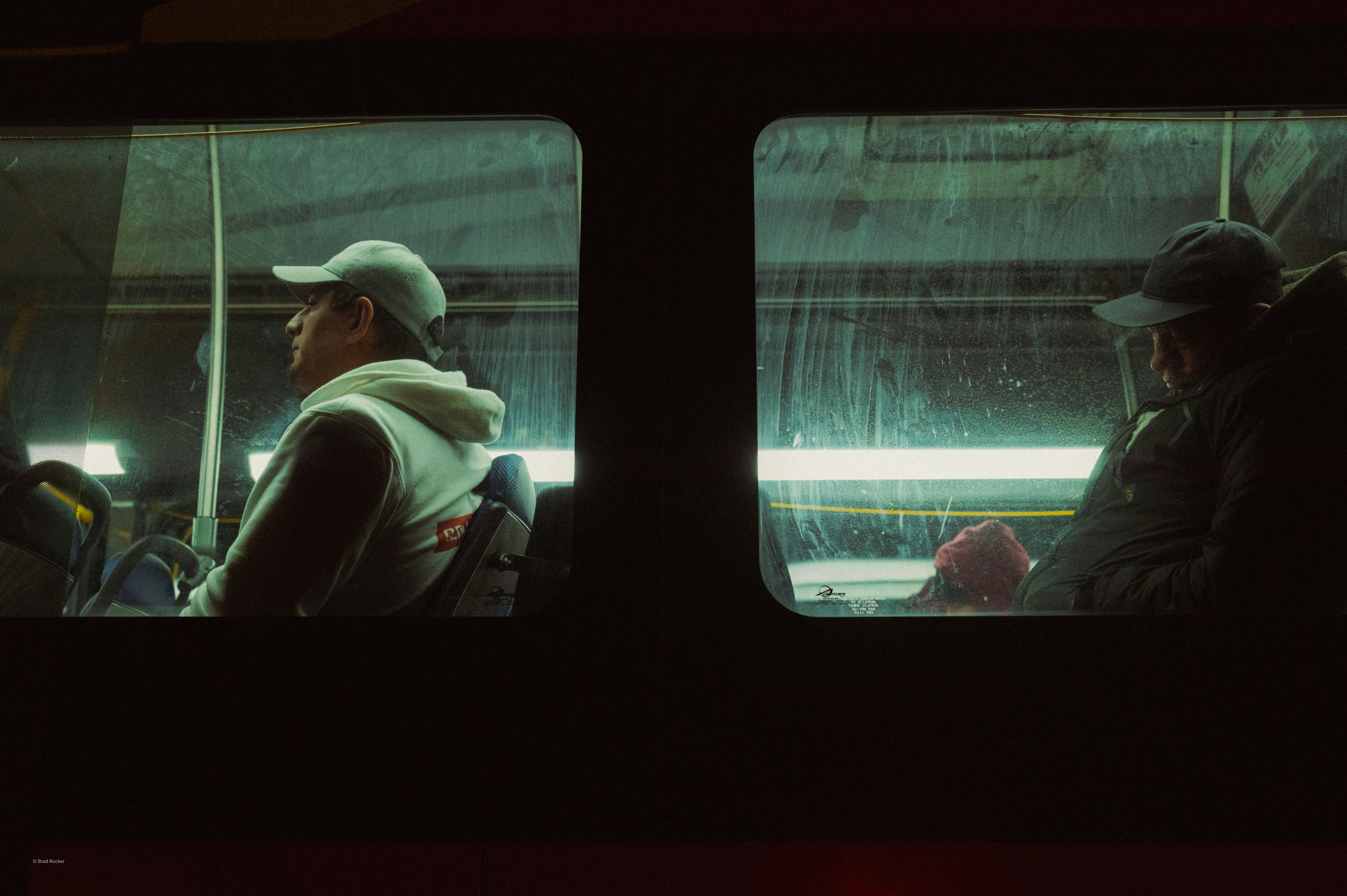 Two people sit on a bus at night.