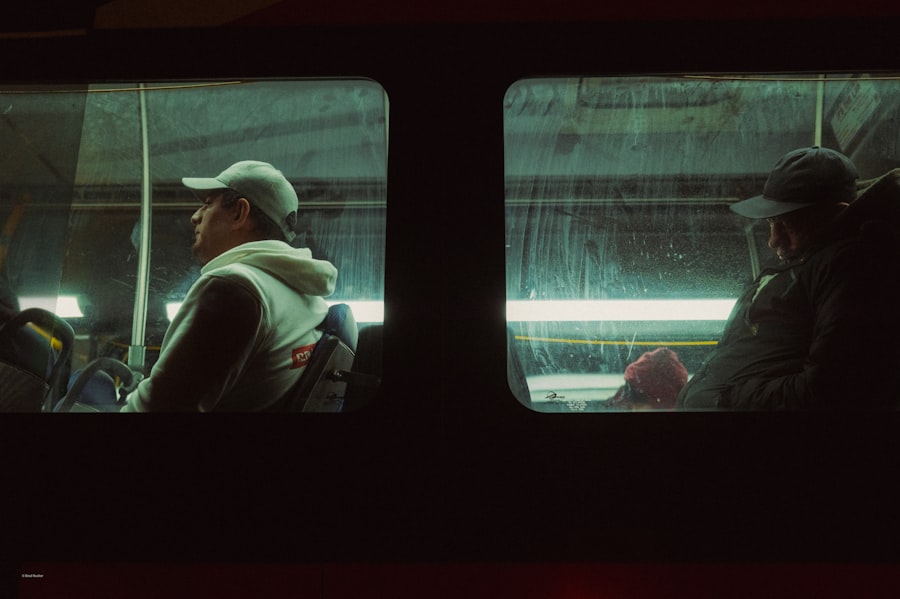 Two travellers sitting on a city bus at night, lit by interior lamps