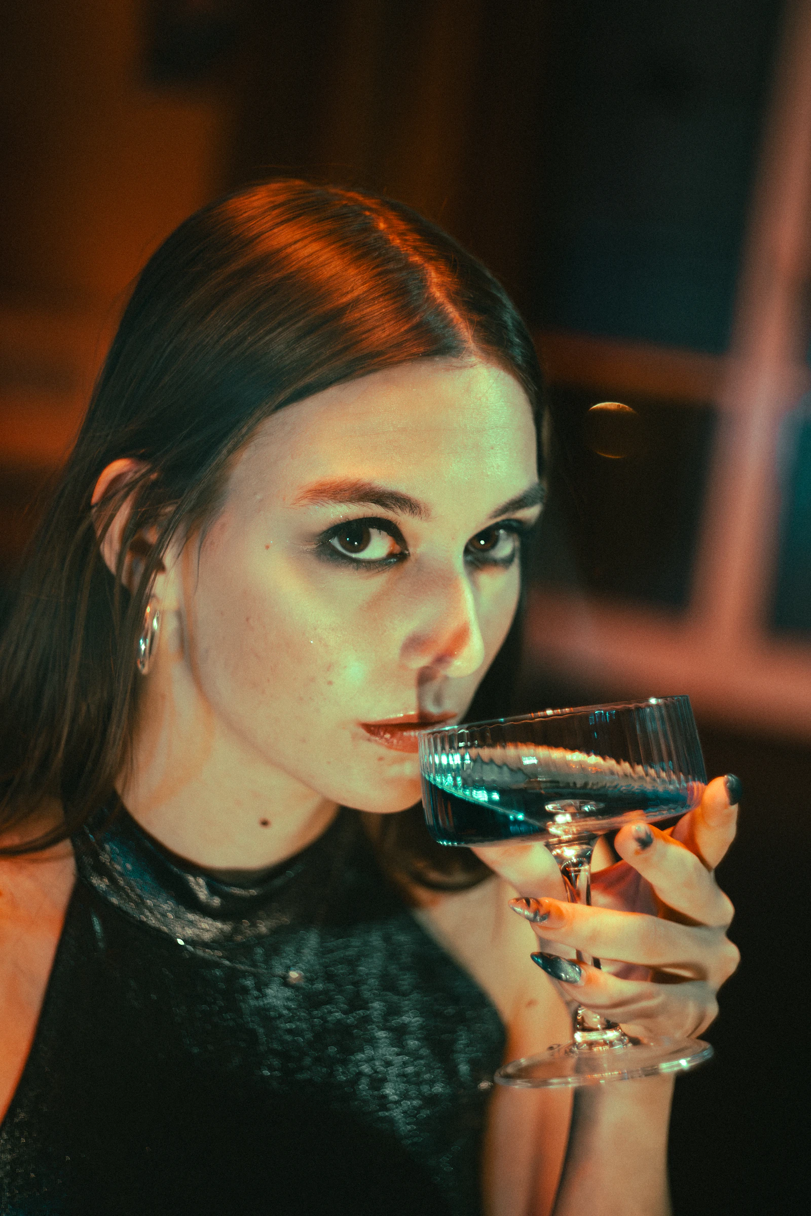 Woman enjoying a blue cocktail in the dim, glowing light of Moonlight Lounge