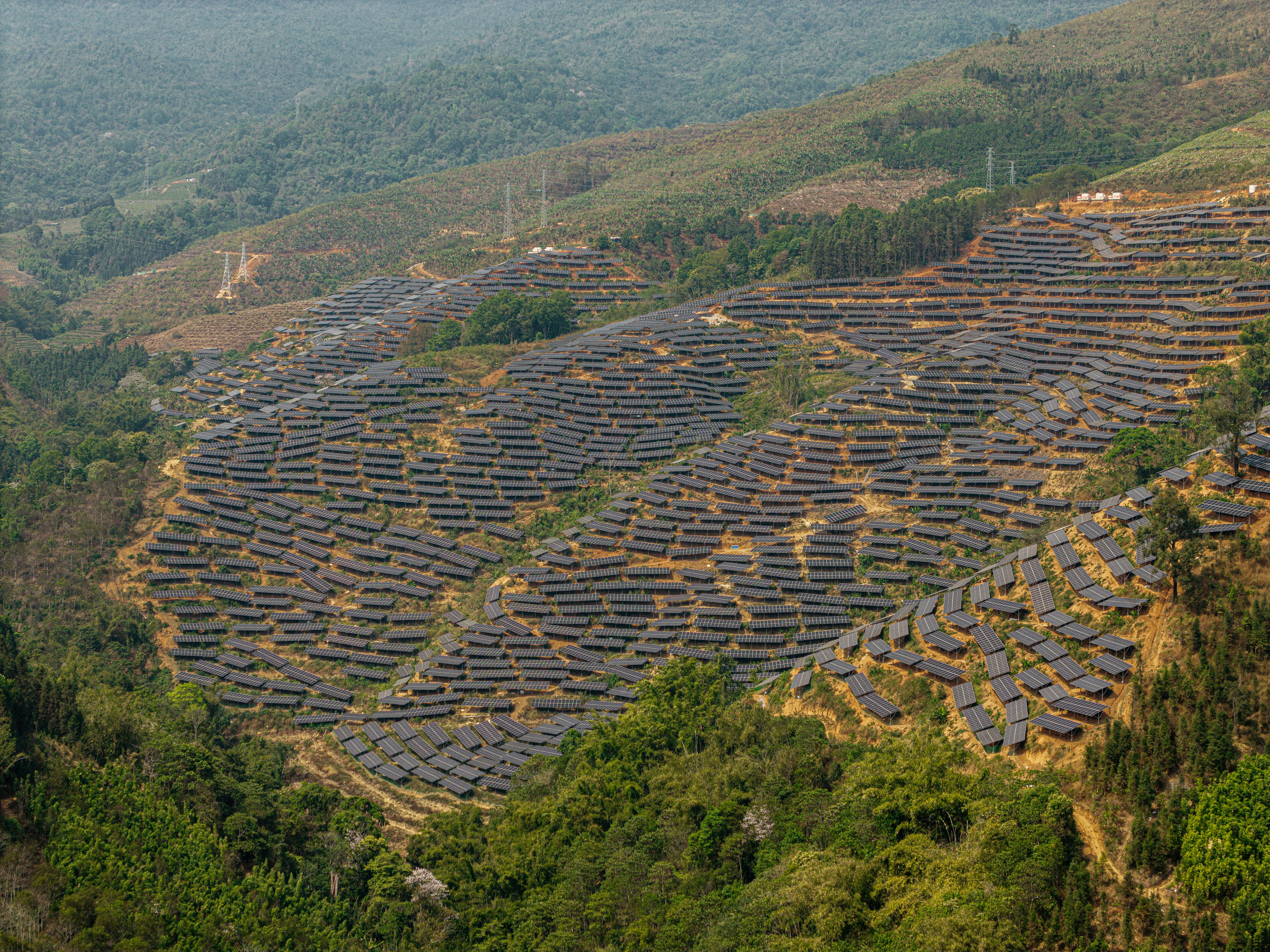 Solar panels cover a hillside in a rural landscape.
