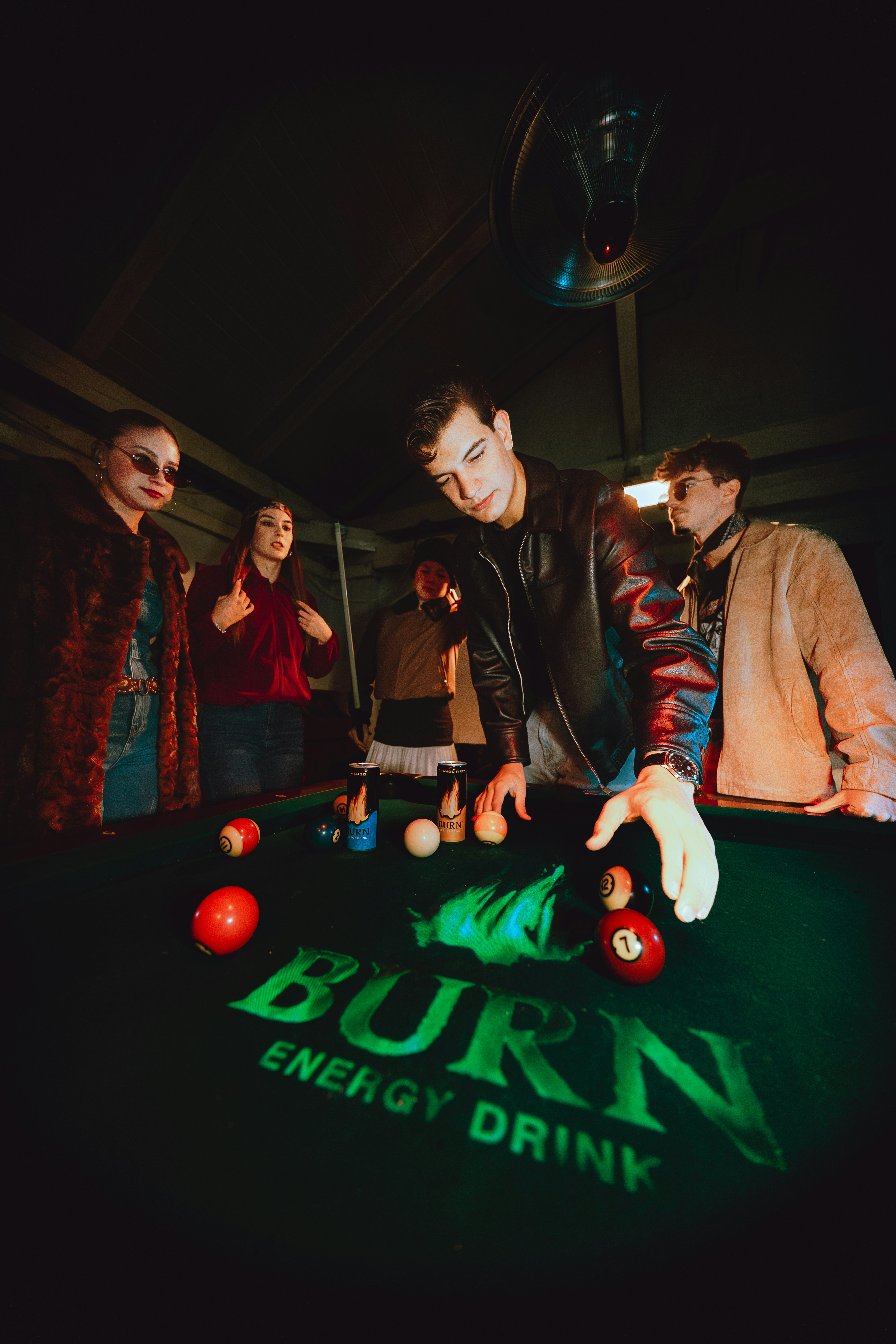 Group of friends playing pool in a dimly lit room