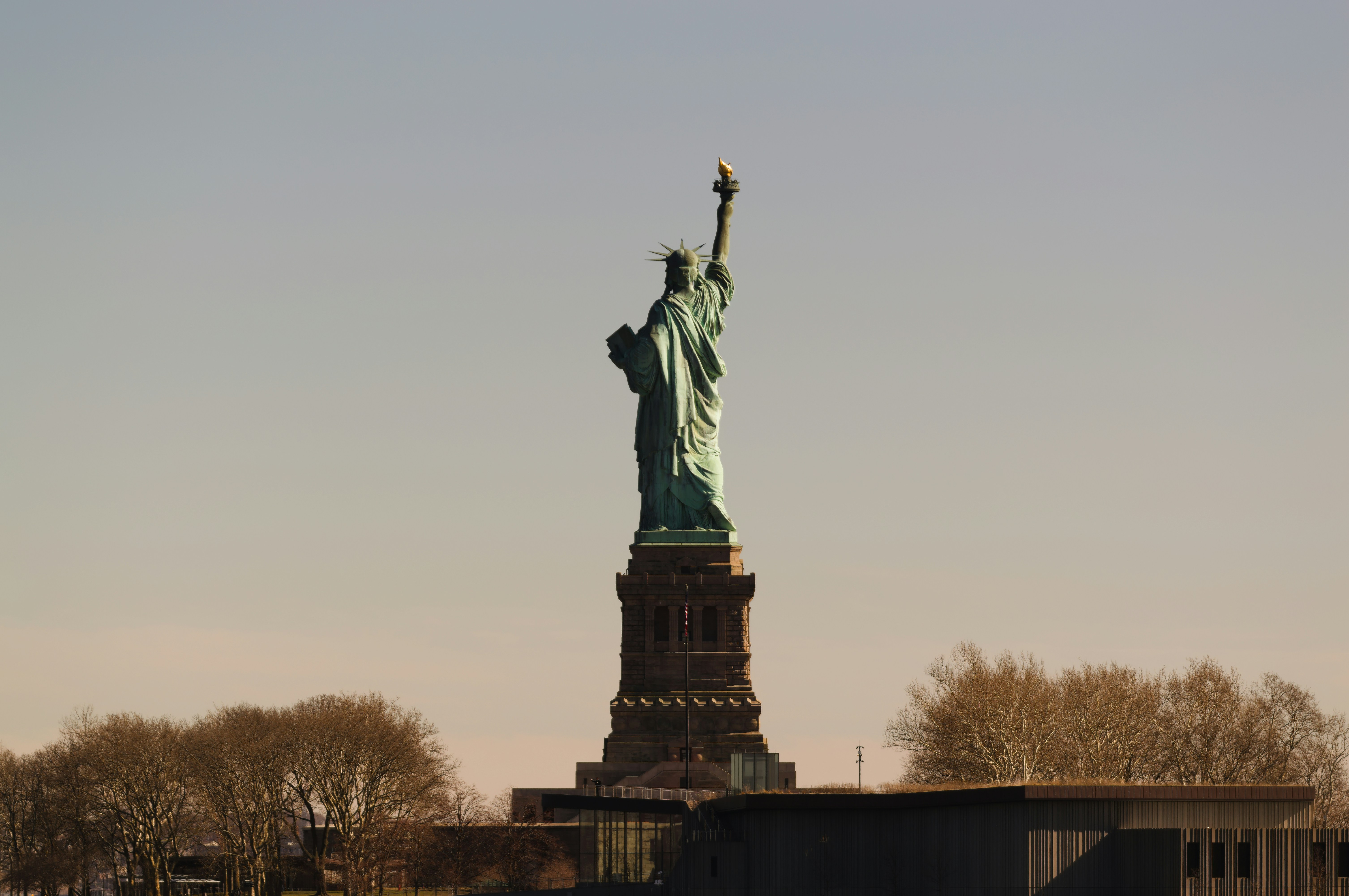 The statue of liberty stands against a clear sky.