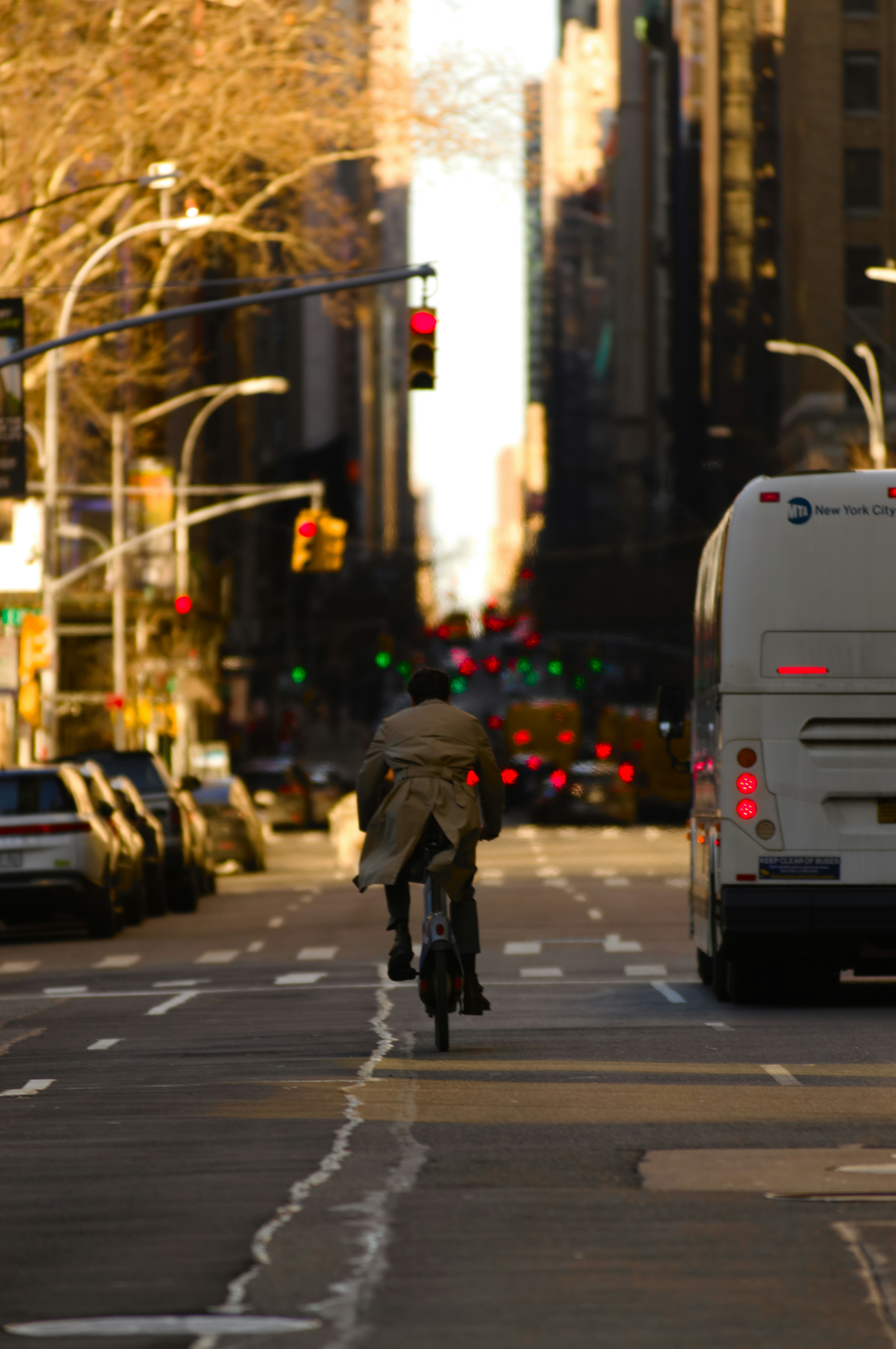 Man rides bicycle down a city street with traffic.