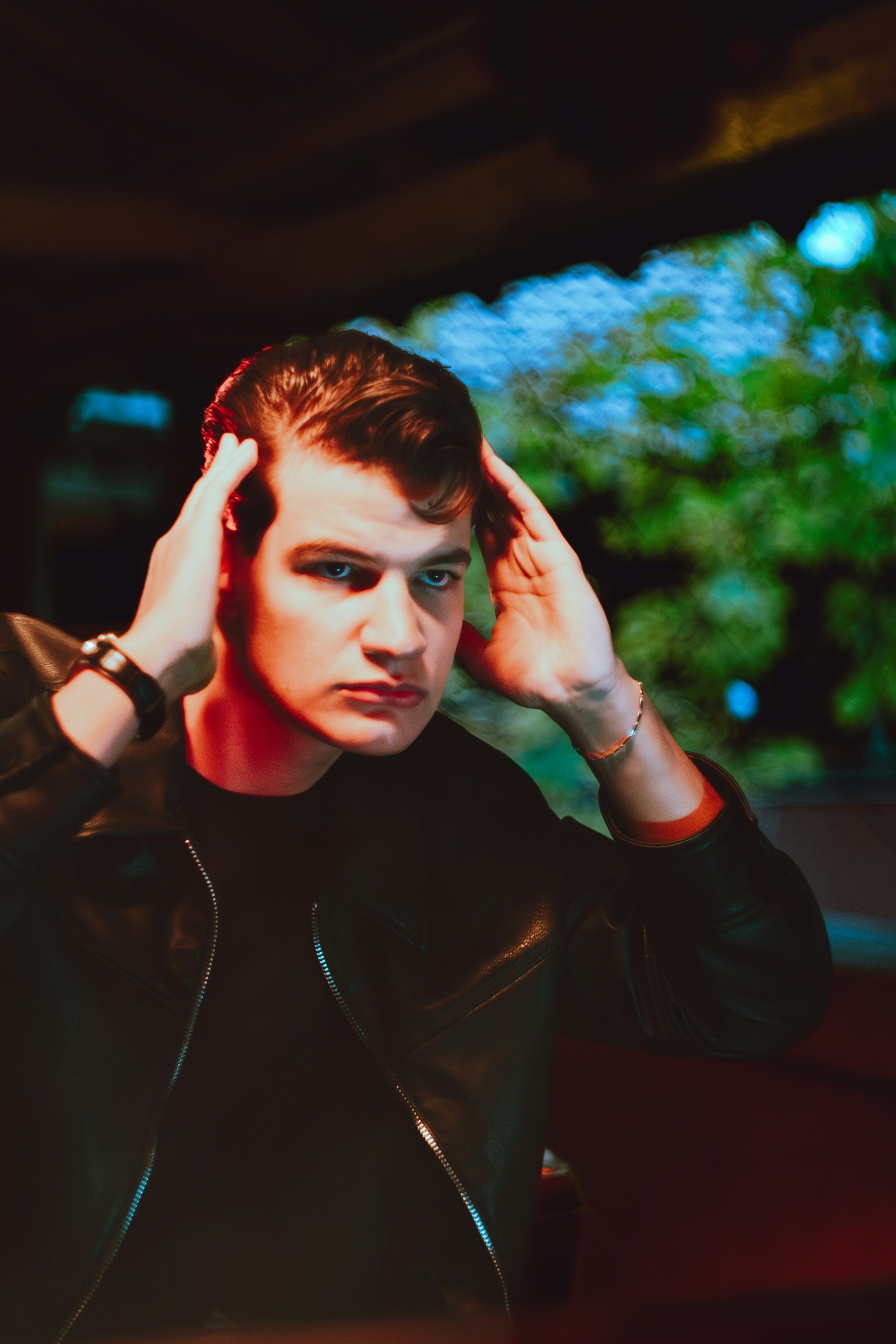 Young man with slicked-back hair adjusting his hairstyle