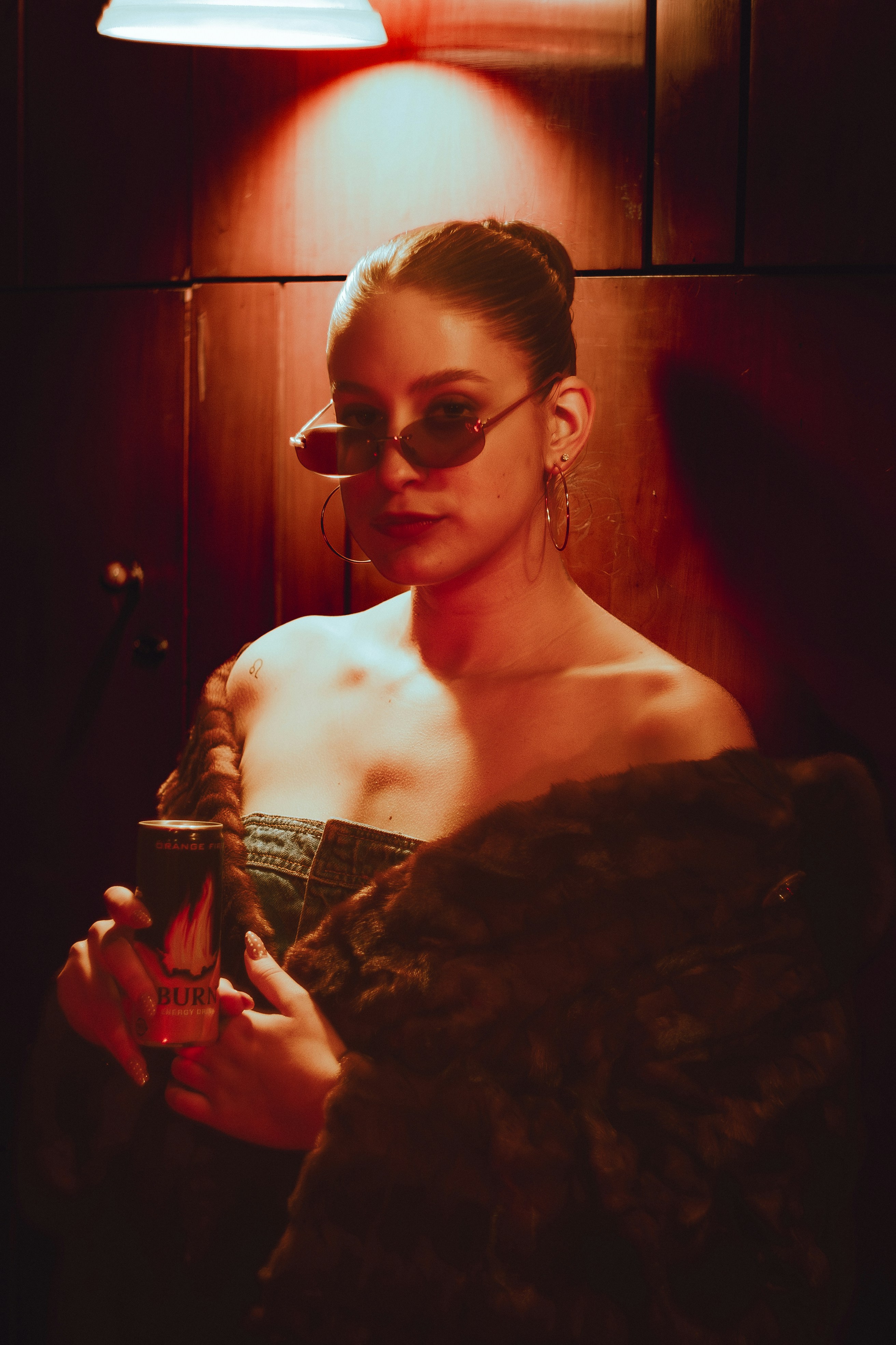 Woman in sunglasses holding a drink with fur stole