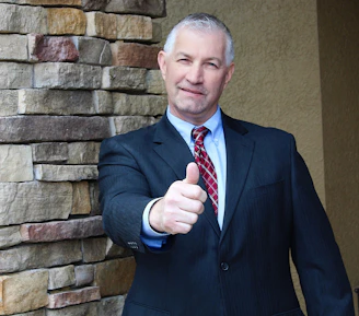 Man in suit gives a thumbs up gesture.