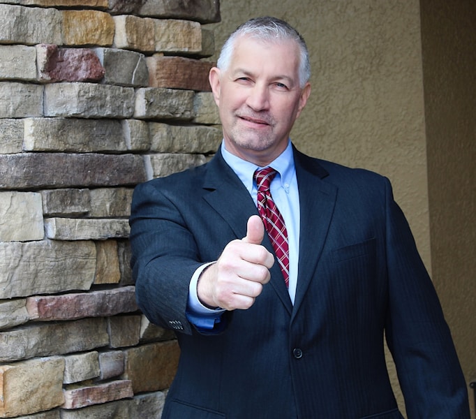 Man in suit gives a thumbs up gesture outside a local business