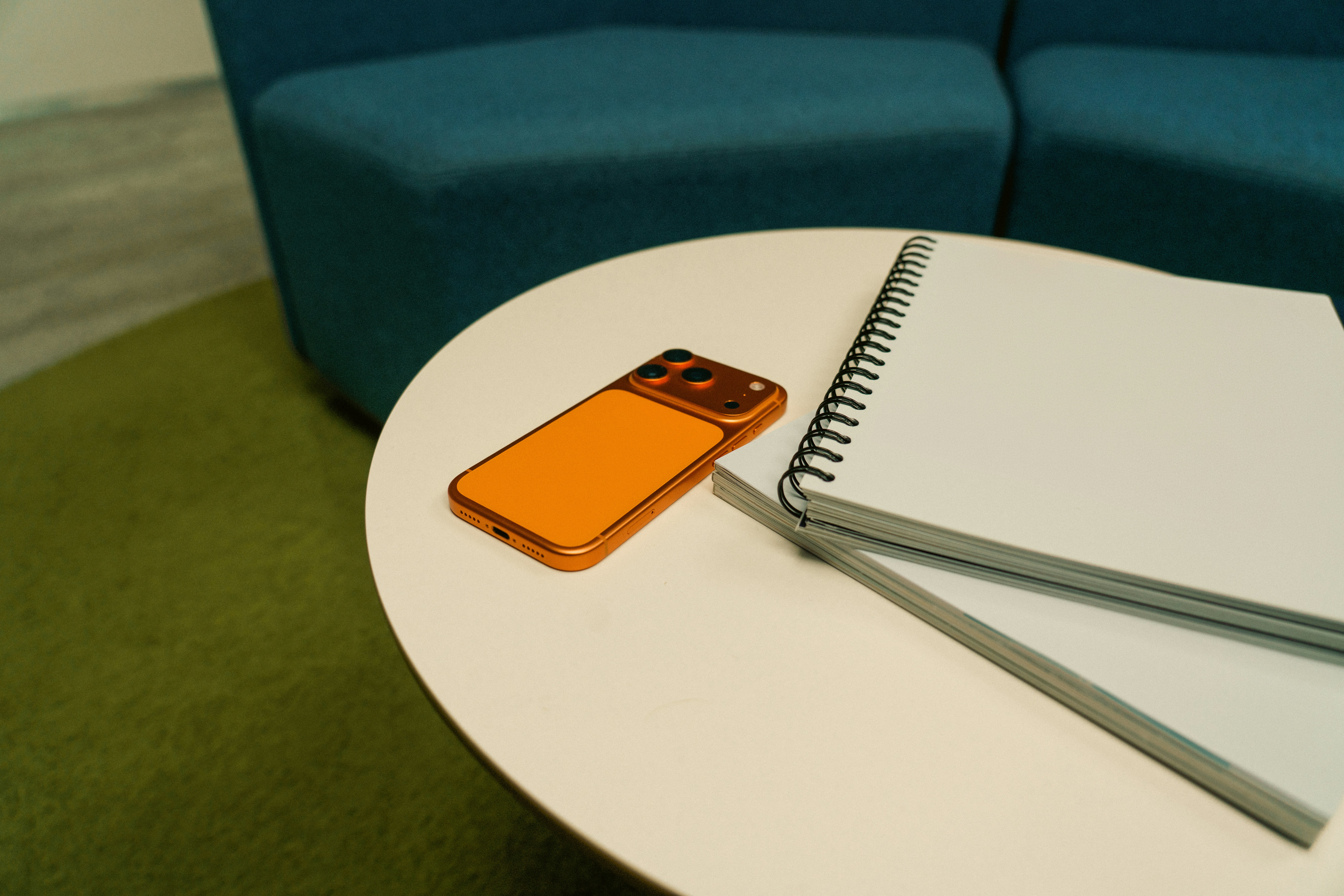 Orange phone and notebook on a white table.