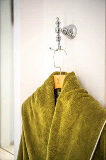 A plush green bathrobe hangs on a wall hook