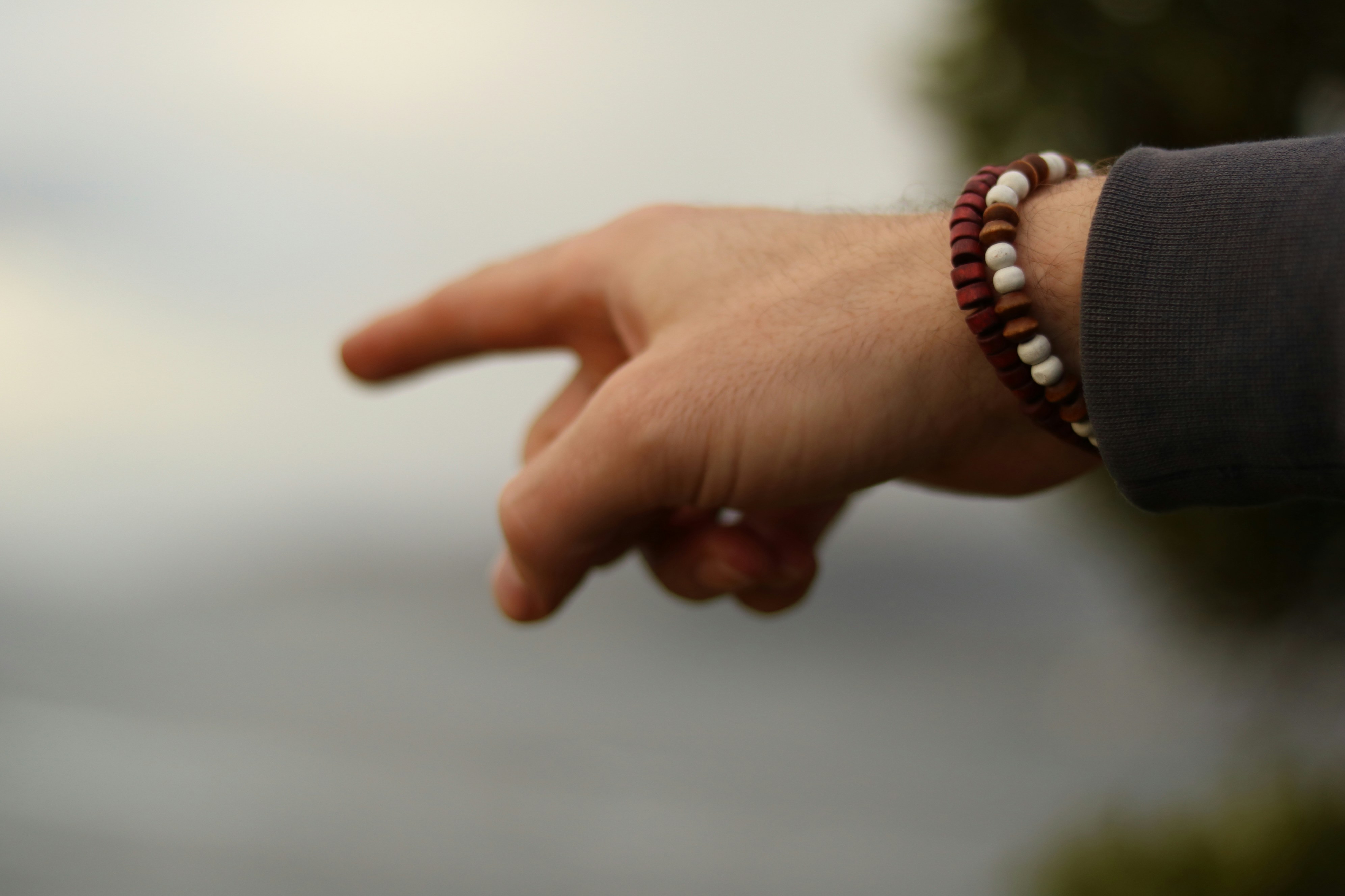 Una mano che indica a sinistra con un braccialetto.