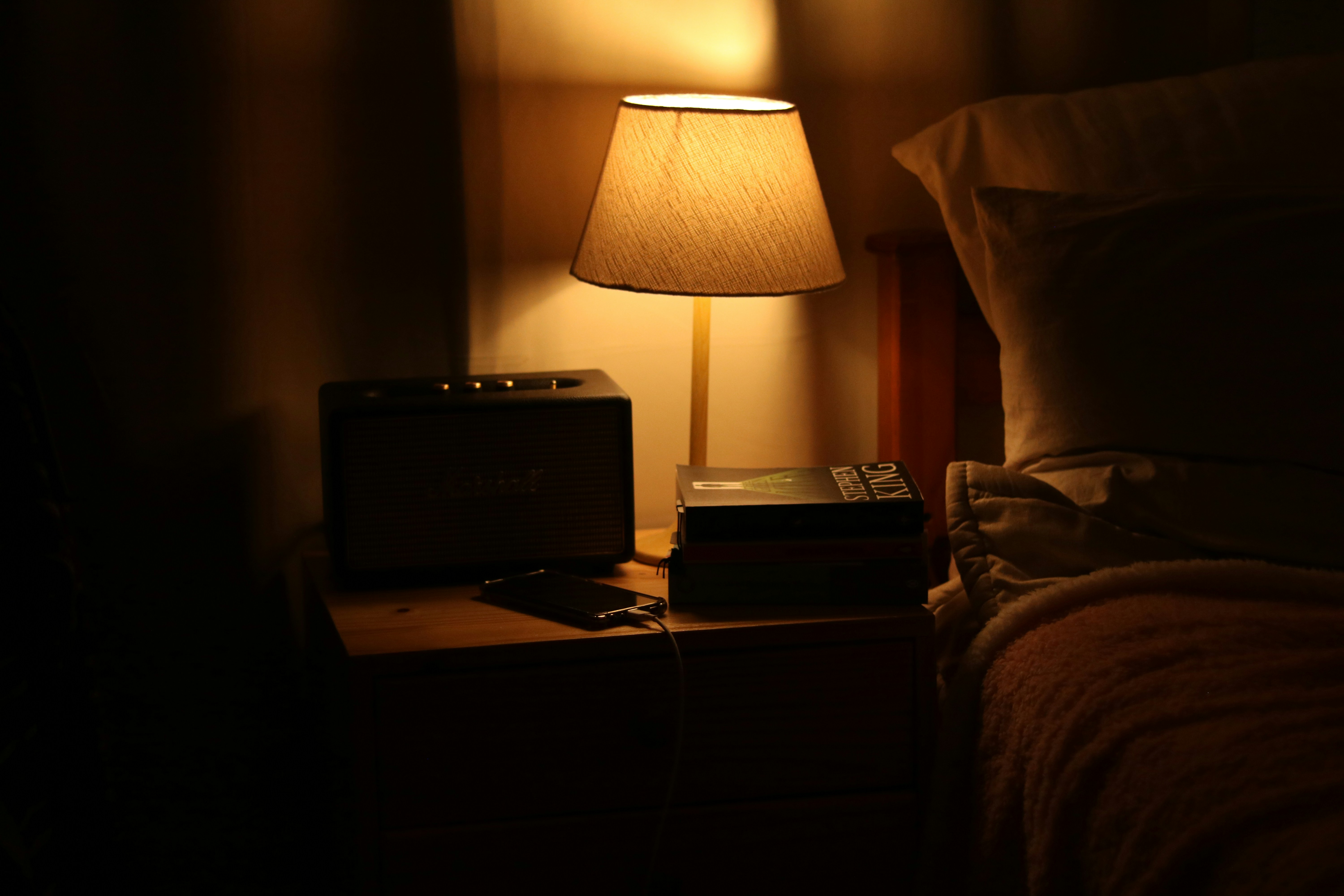 A bedside lamp illuminates a nightstand with a radio.