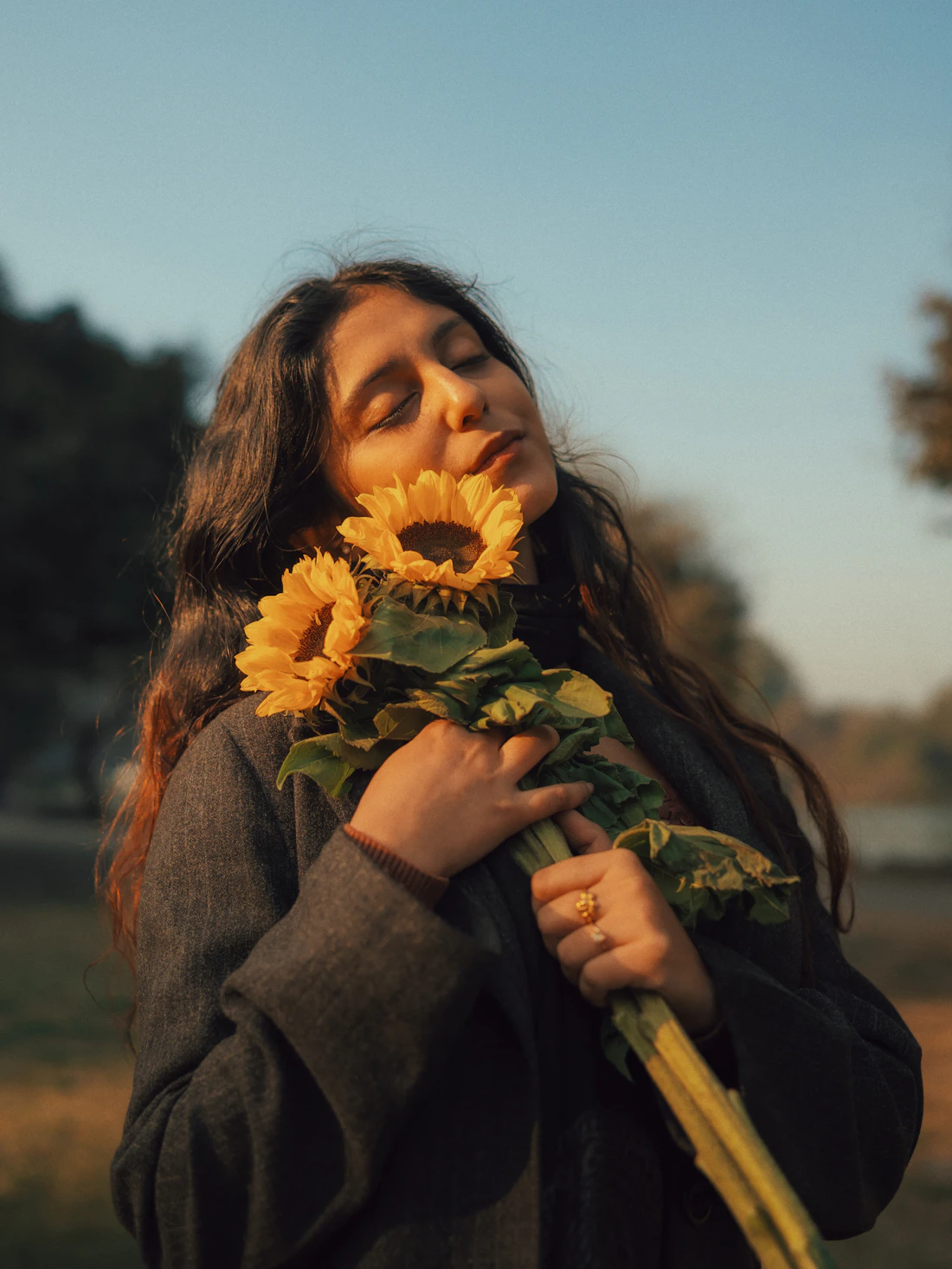Woman holding sunflowers with her eyes closed in golden light