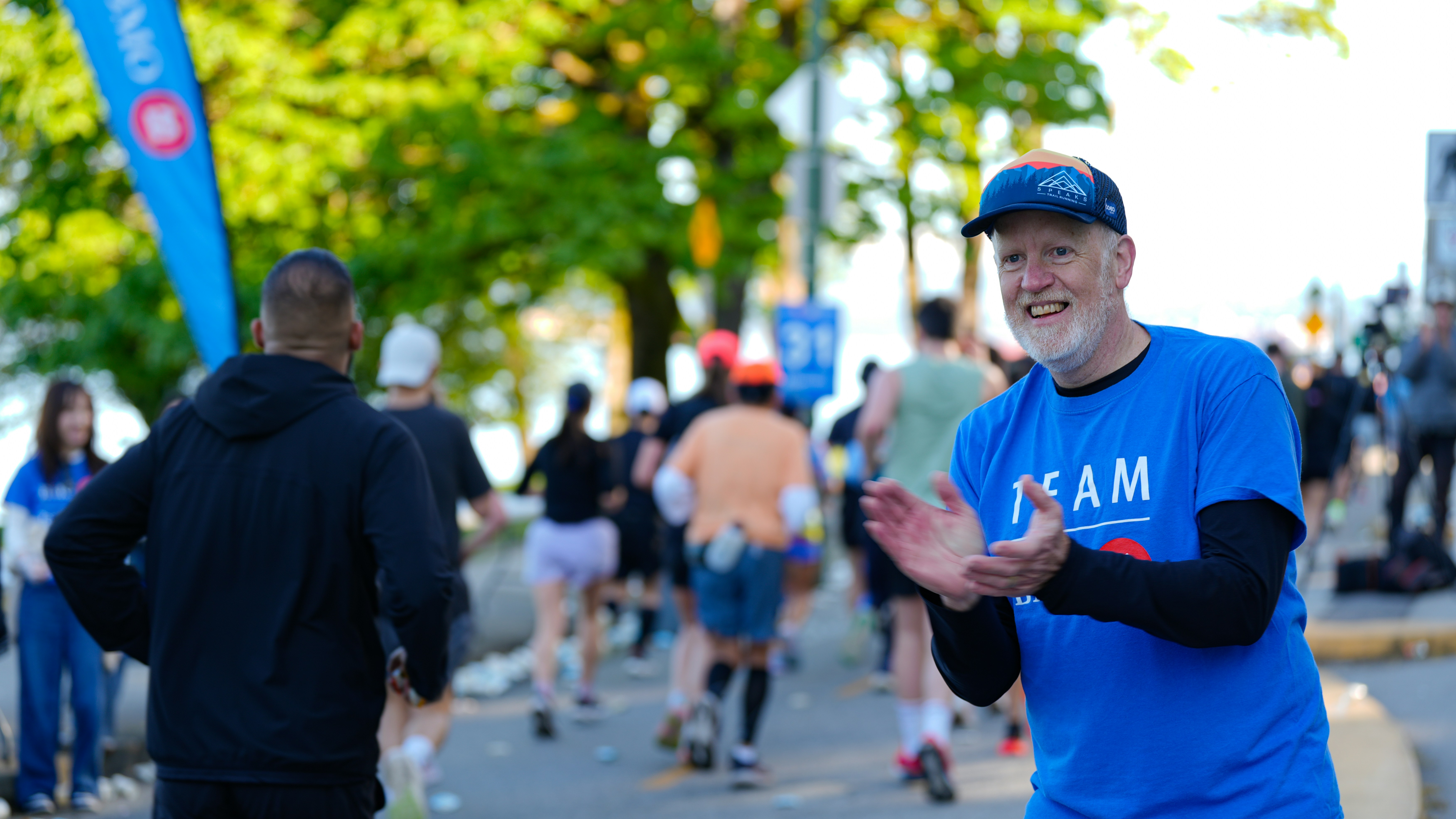 Man in blue shirt cheers on marathon runners