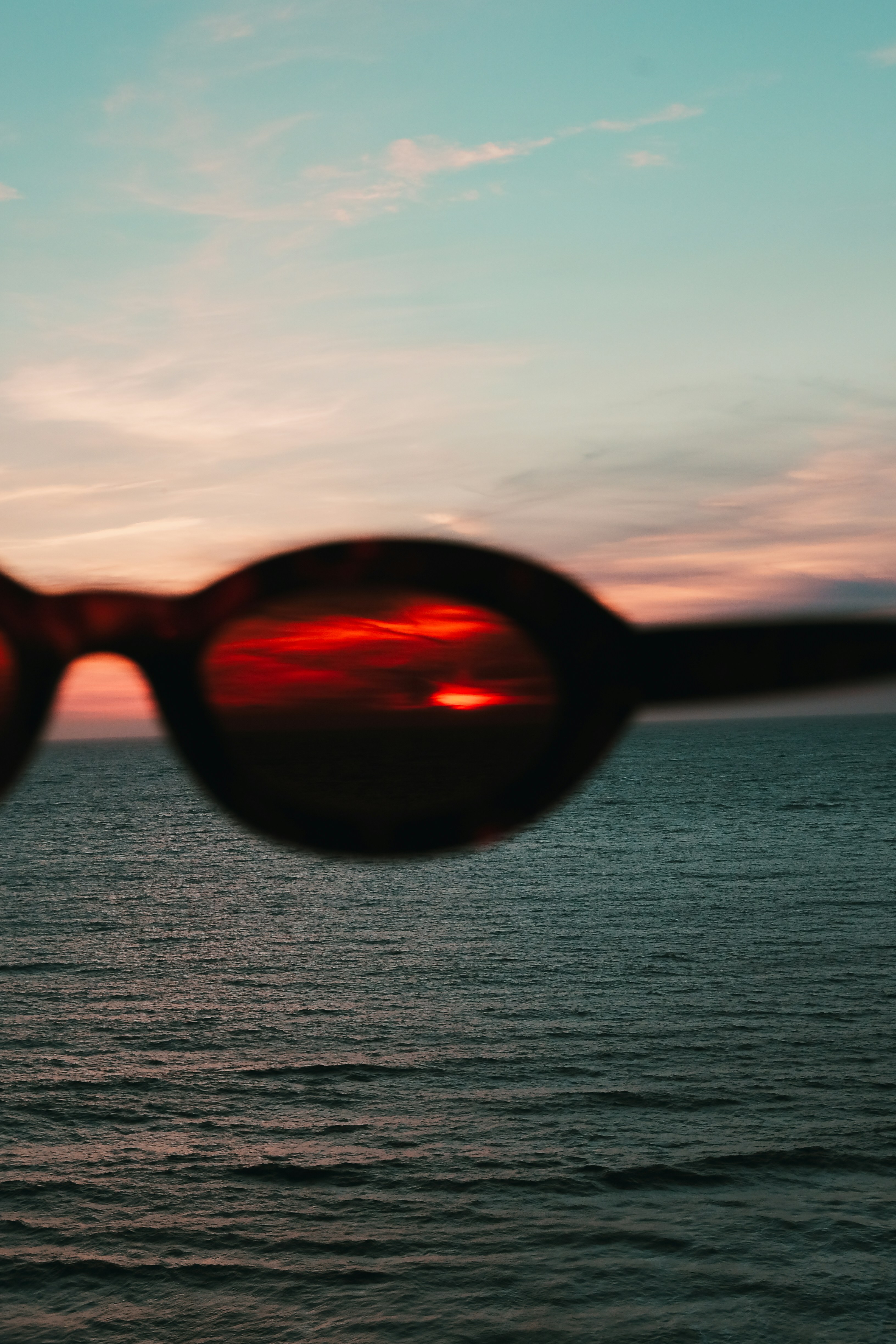 Pôr do sol visto através de óculos escuros sobre o oceano
