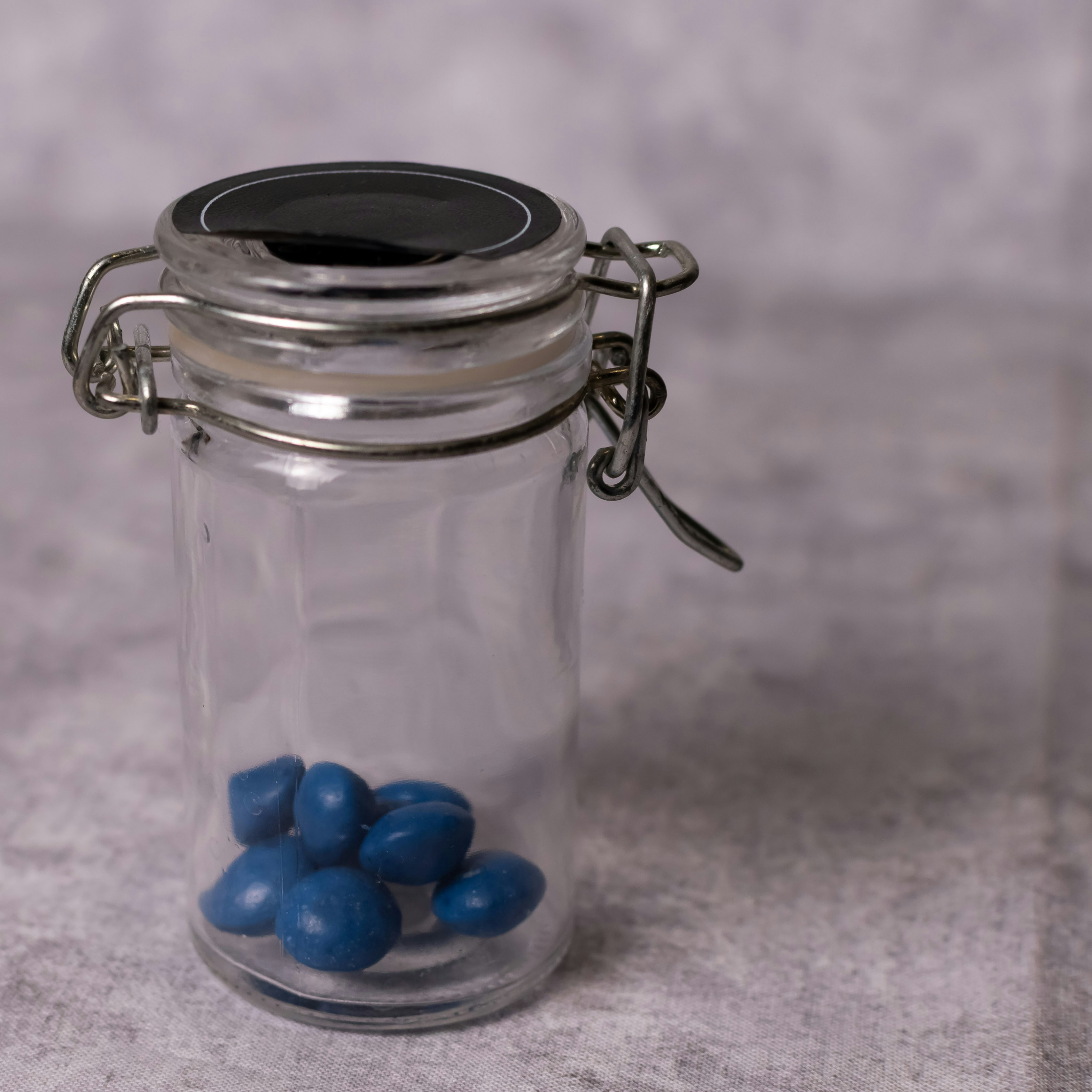 A small glass jar with blue candies inside