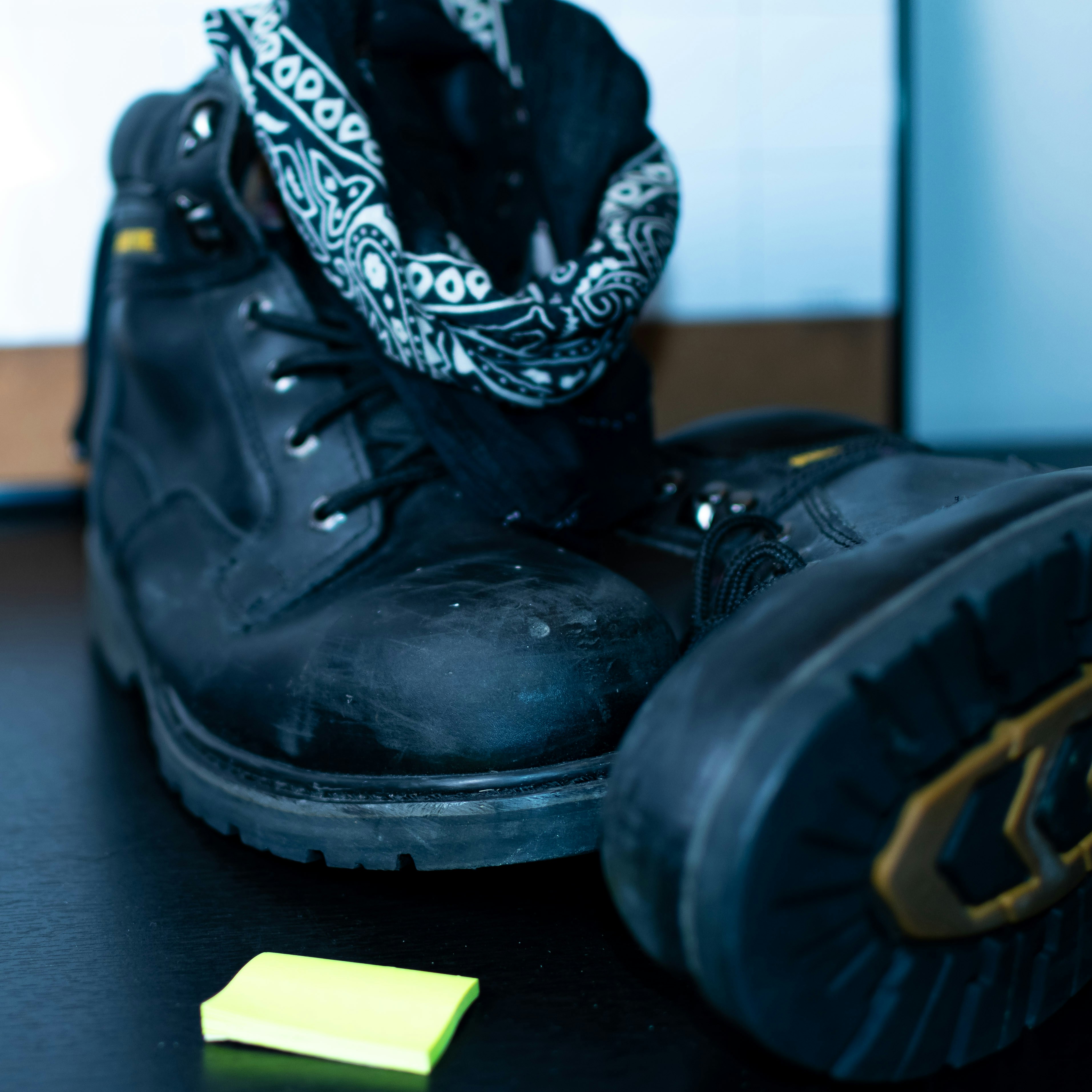Black work boots with bandana and sticky note.
