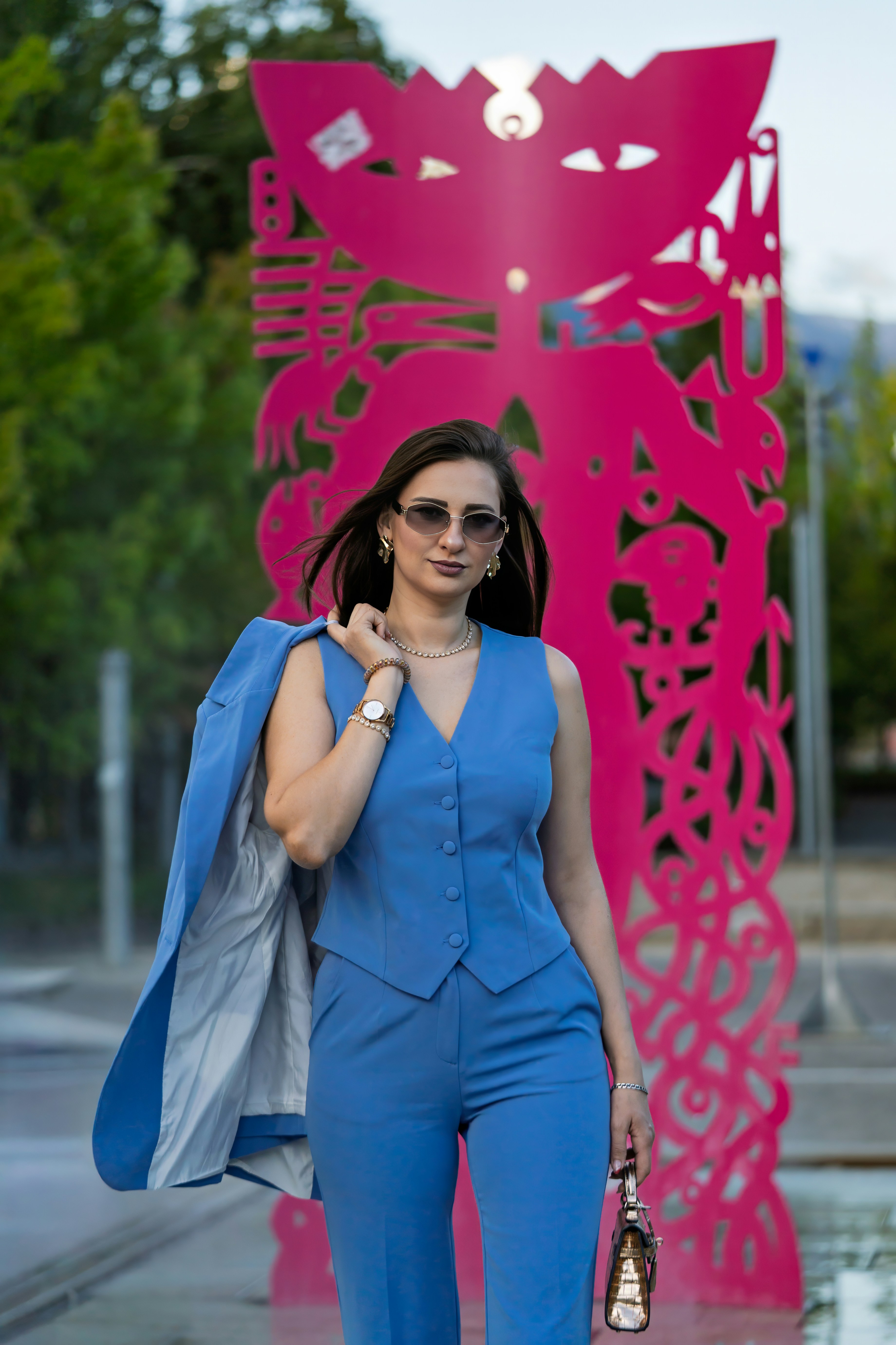 Donna in abito blu passa accanto a una scultura rosa