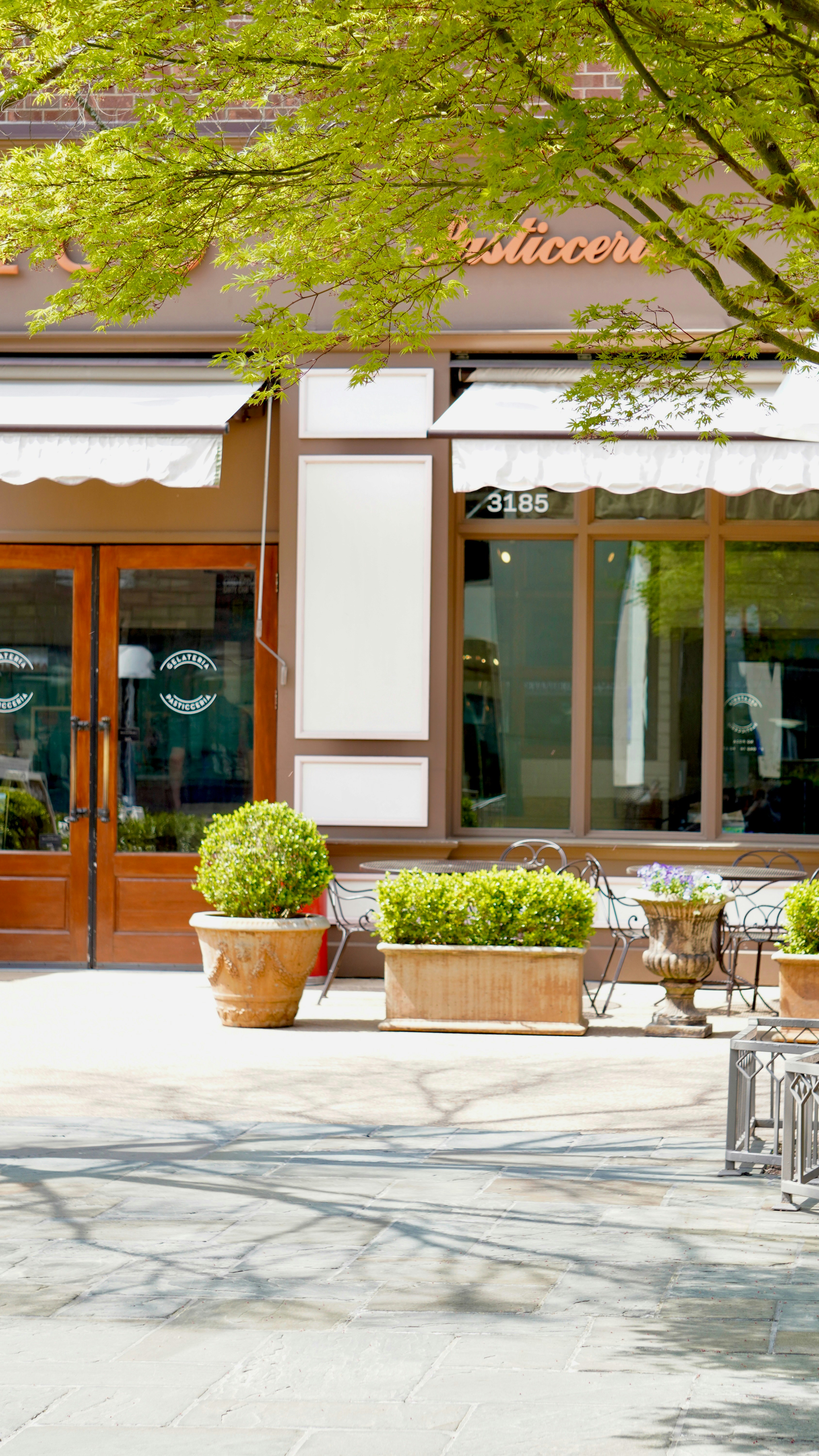A storefront with awnings and potted plants