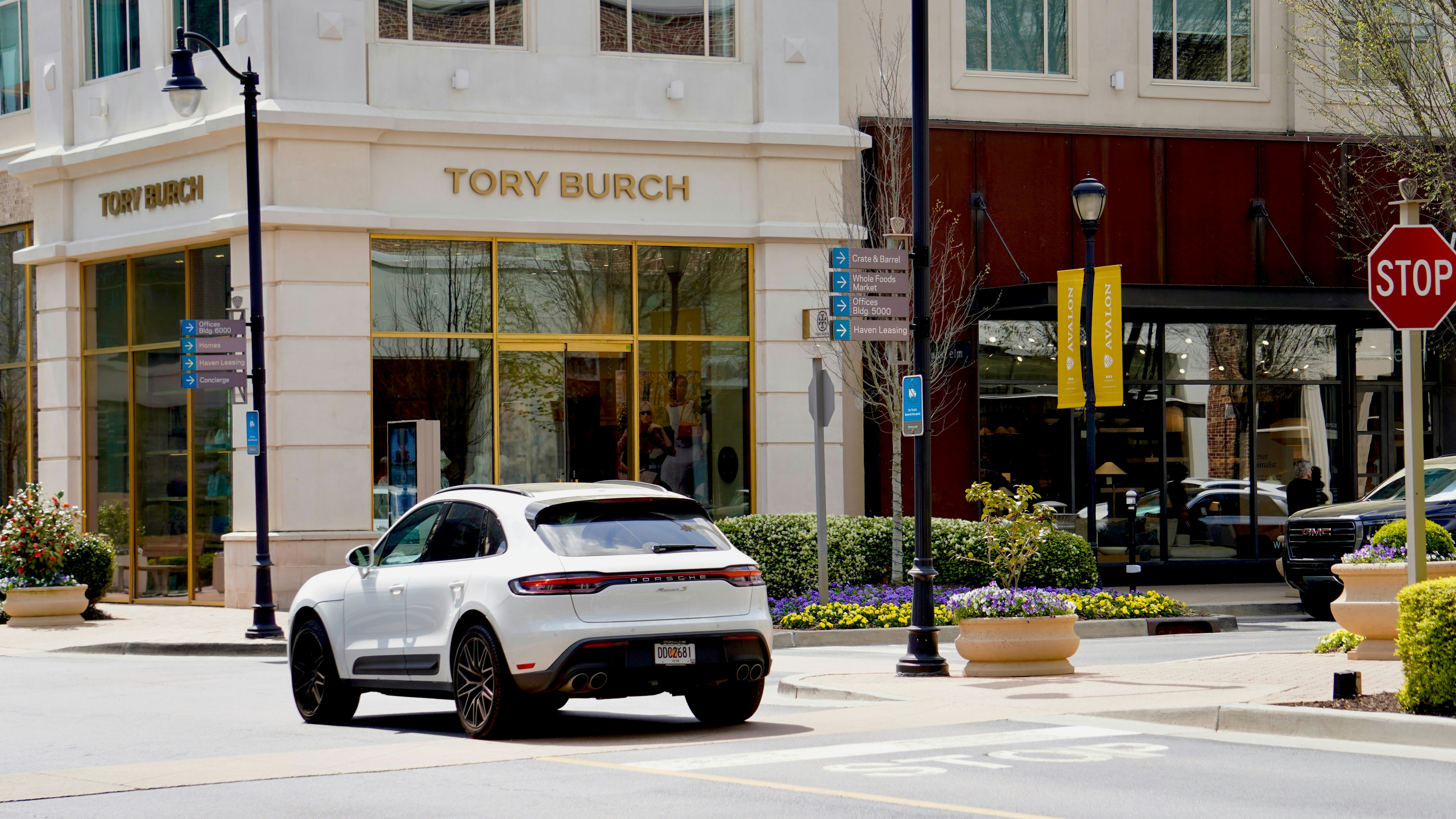 White porsche suv near a tory burch store.