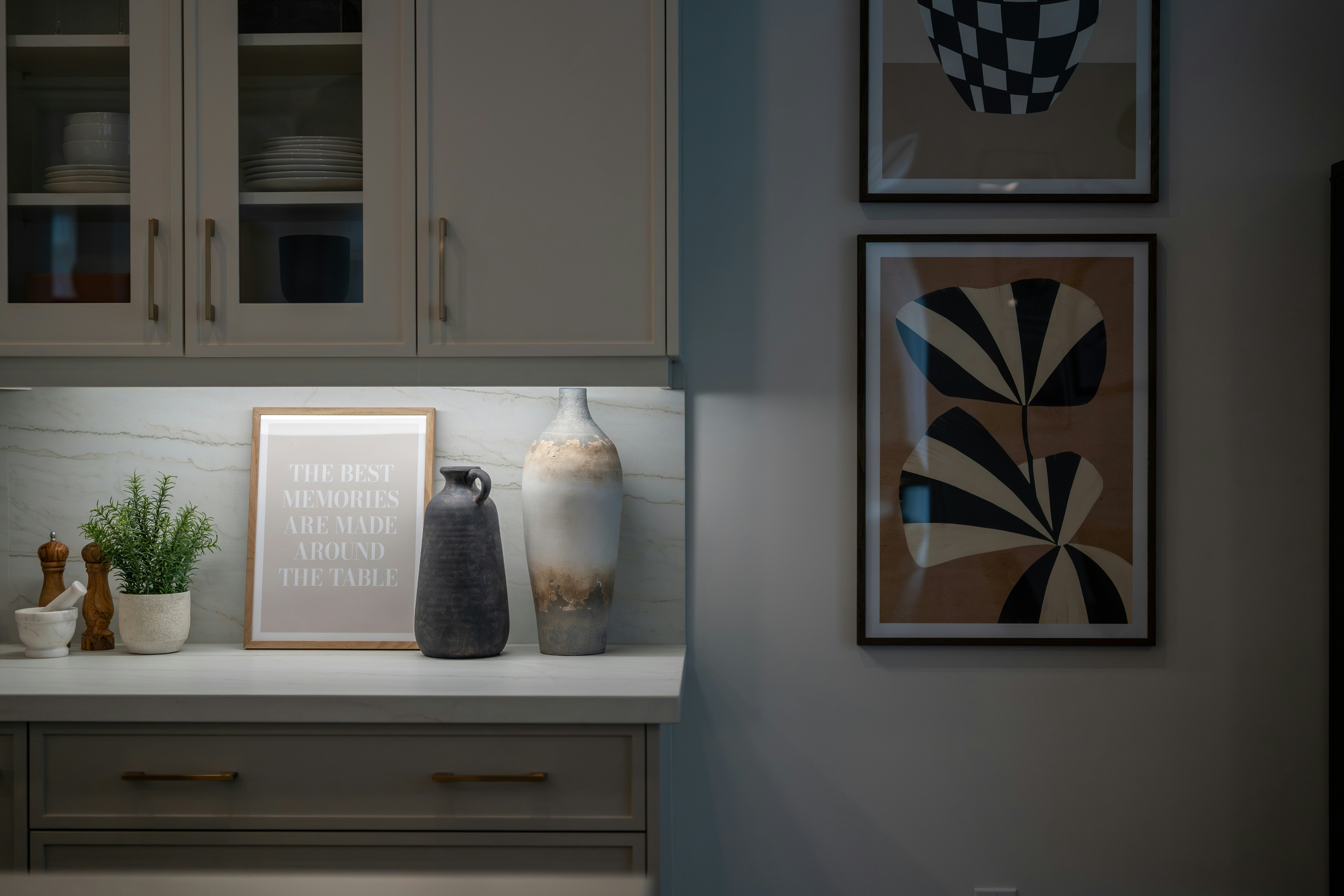 Modern kitchen counter with decorative vases and framed art.