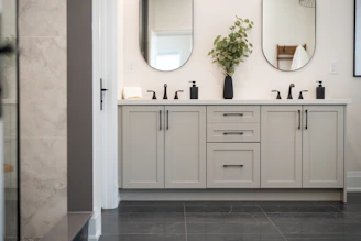 A modern bathroom vanity with two sinks and mirrors.