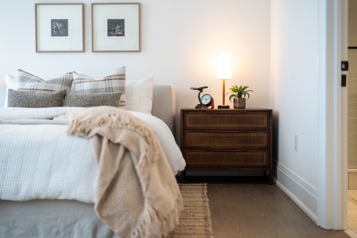 cozy apartment bed with throw blanket and plaid pillows, framed art prints above instead of headboard