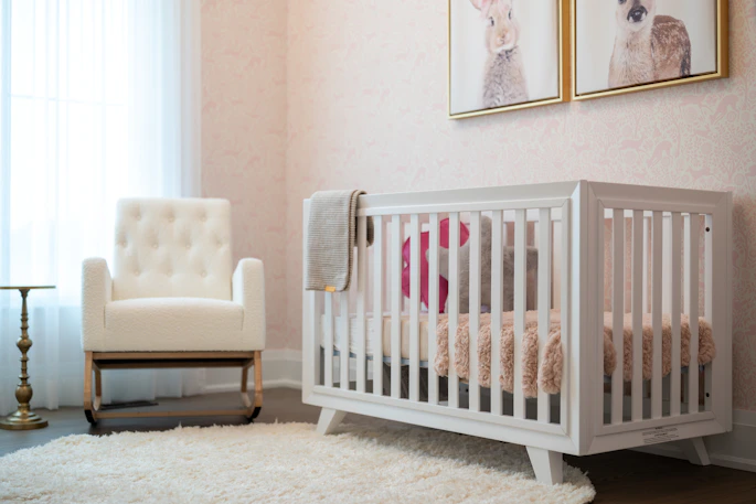 A cozy nursery with a white crib and armchair.