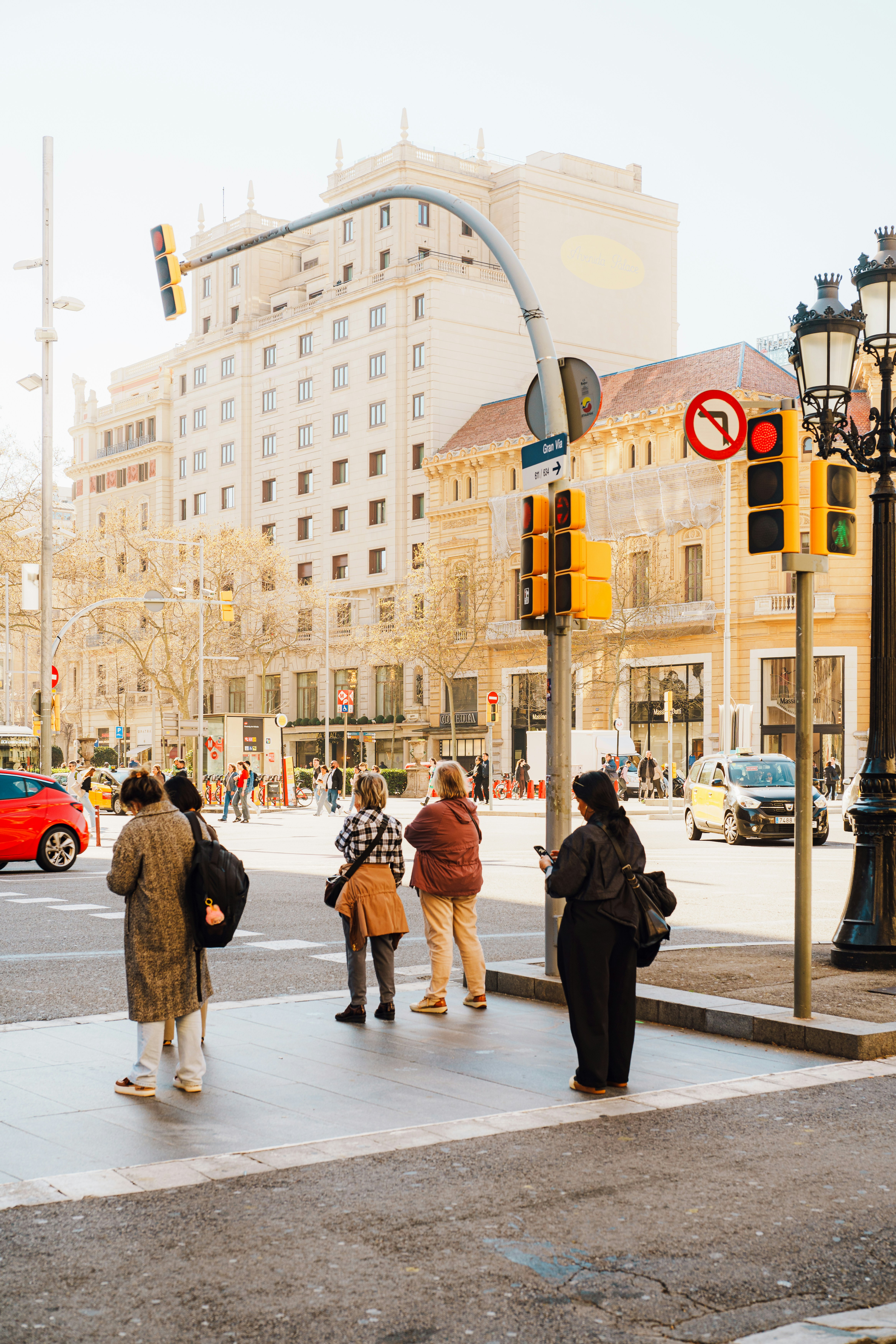 Orang-orang menunggu di persimpangan kota dengan lampu lalu lintas.