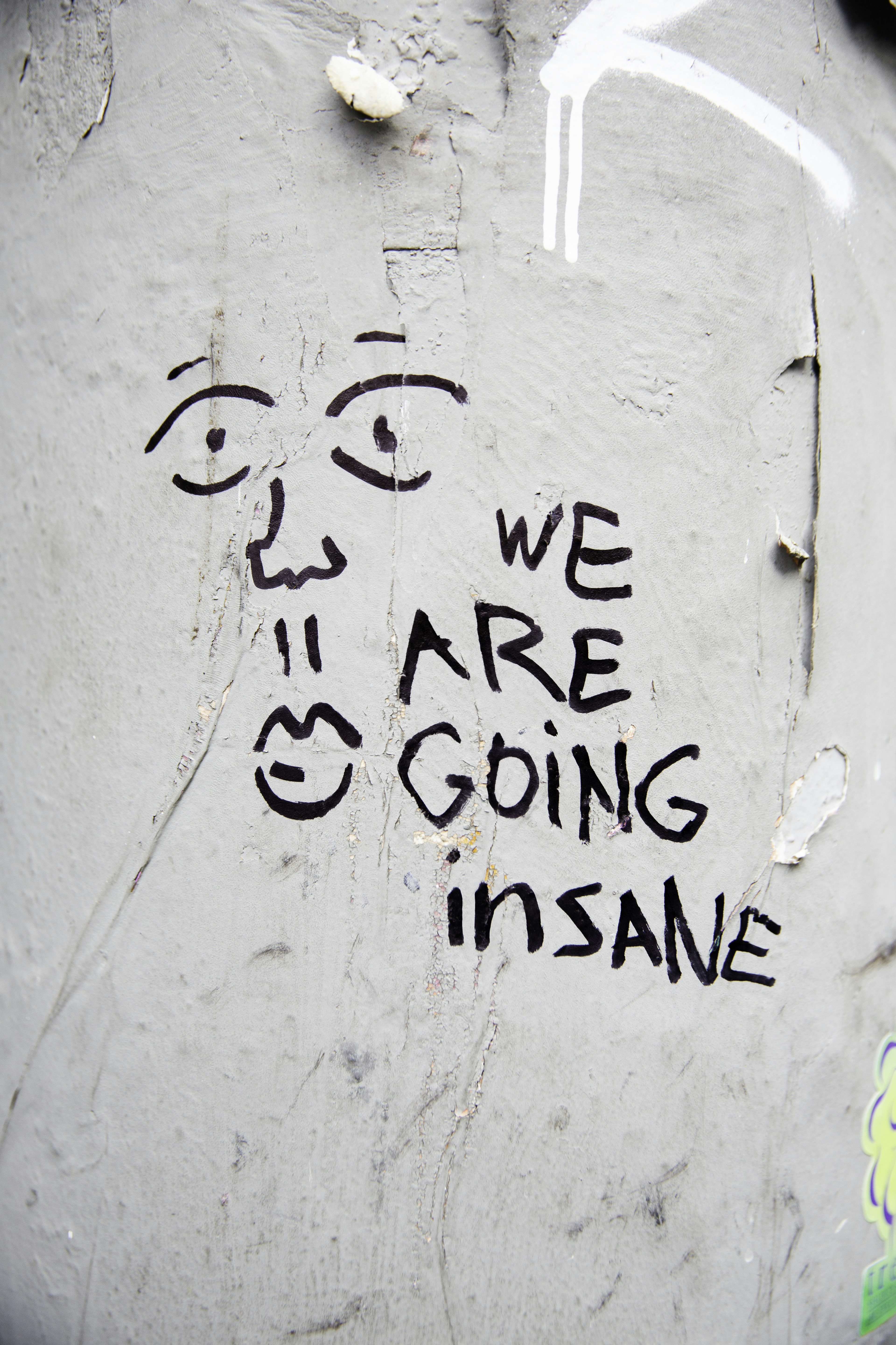 Grafiti wajah dengan teks "kami menjadi gila"