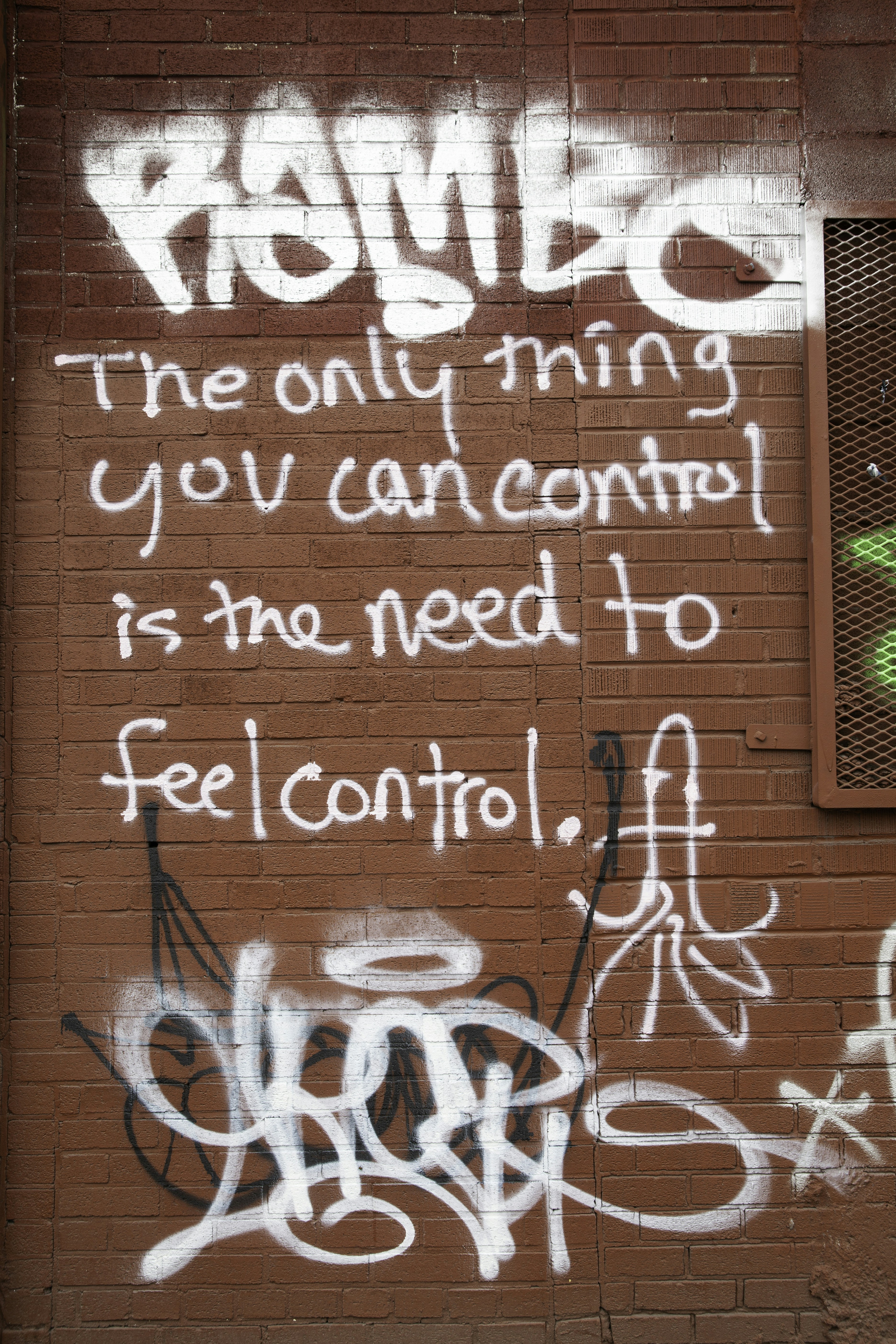 Graffiti on a brick wall with a quote about control.