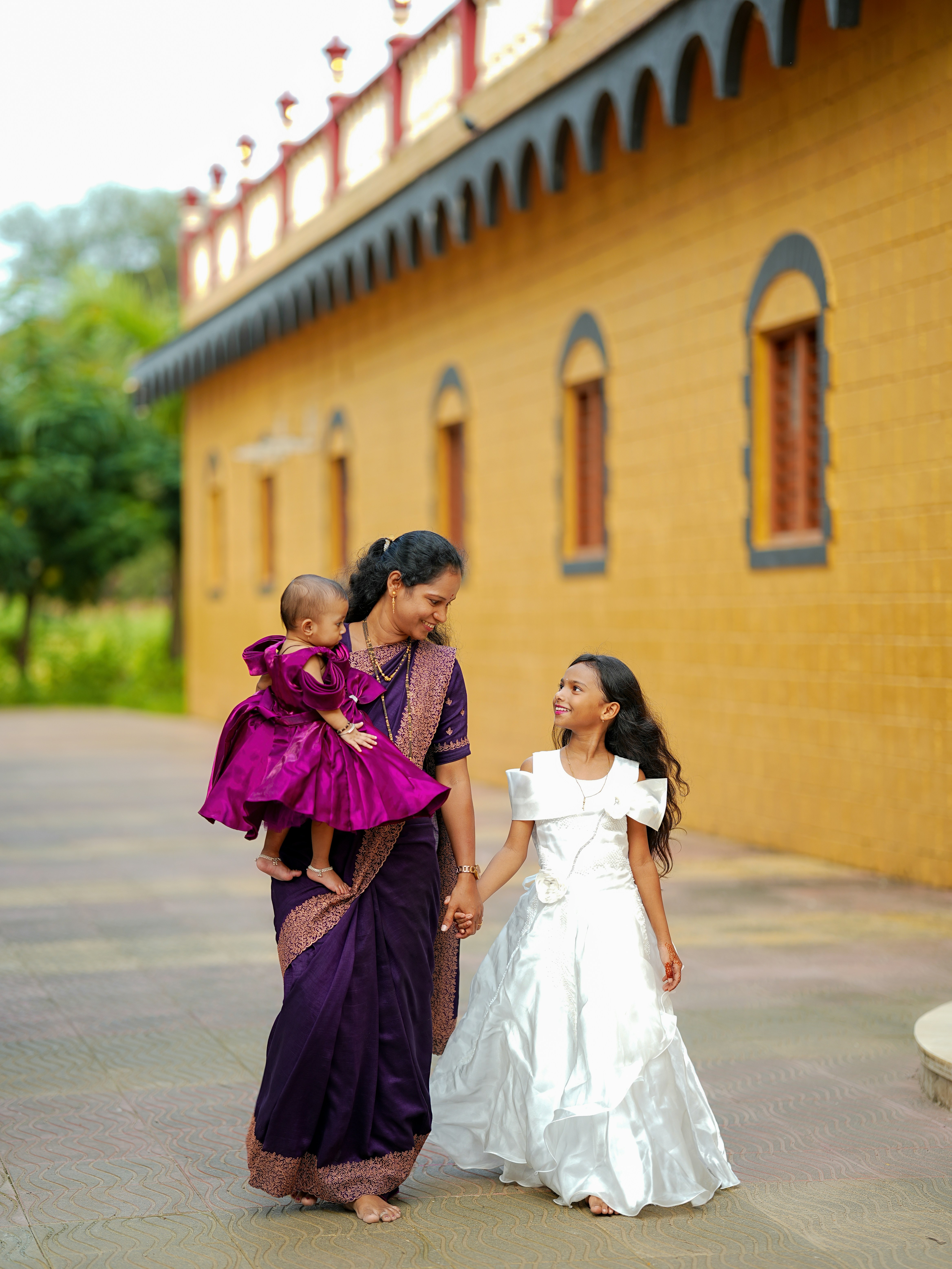 Mother holds baby while walking with daughter.