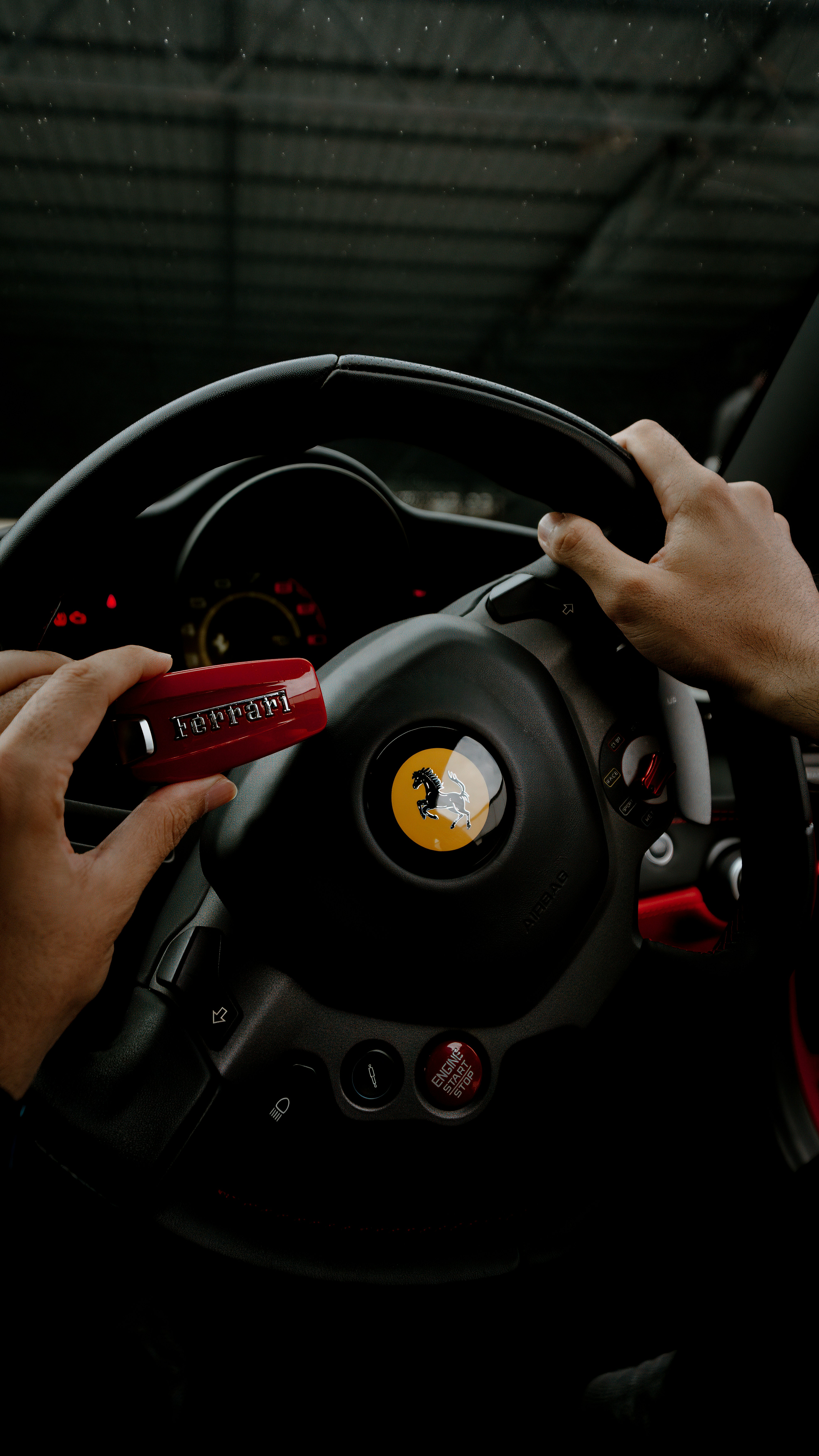 Mani che tengono una chiave Ferrari rossa vicino al volante