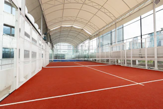 Indoor tennis court with red surface and white lines