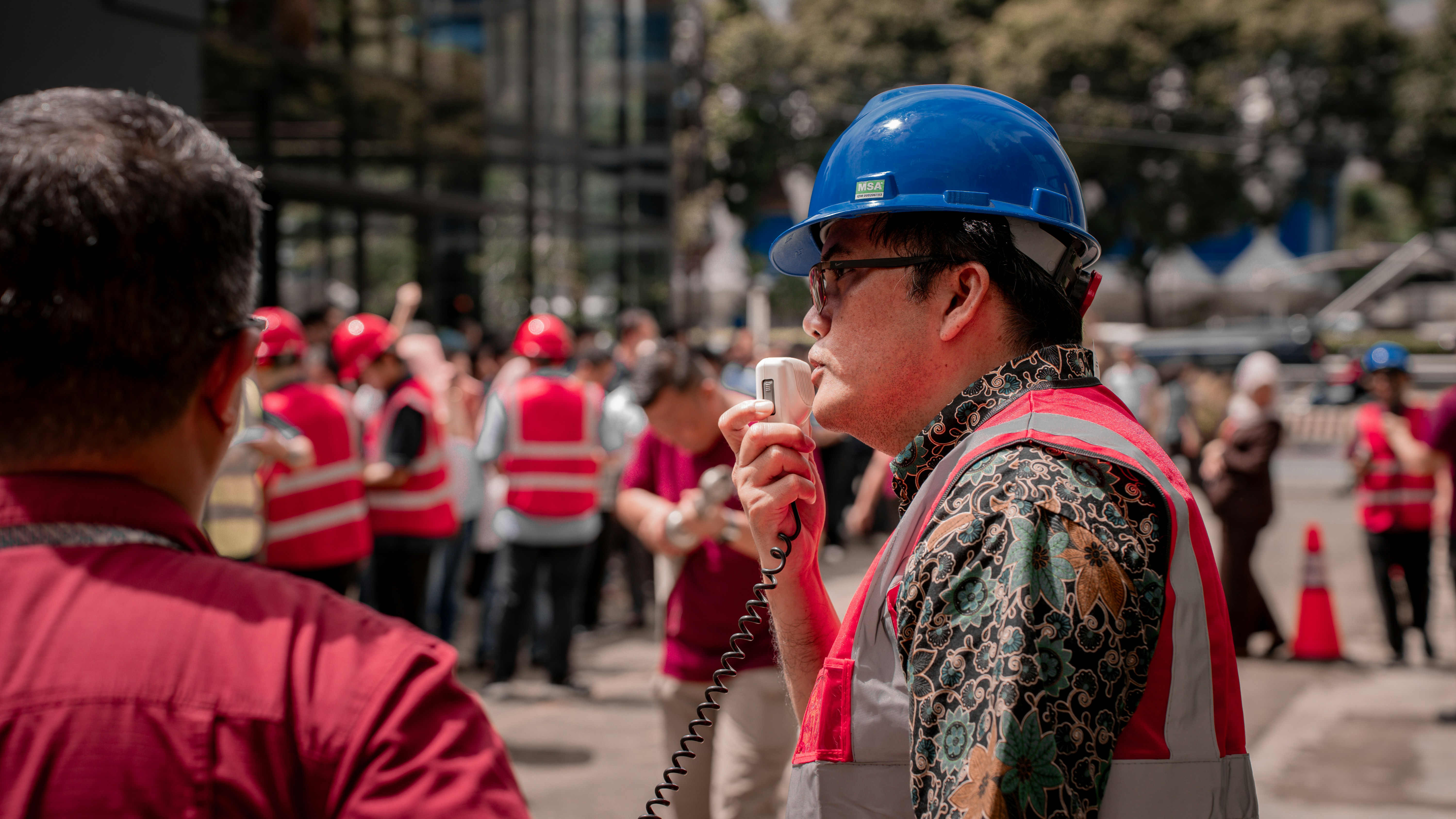 Man in hard hat speaks into a megaphone to workers.
