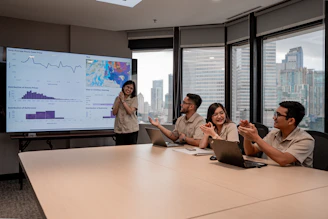 Team collaborates during a business presentation with data on screen.