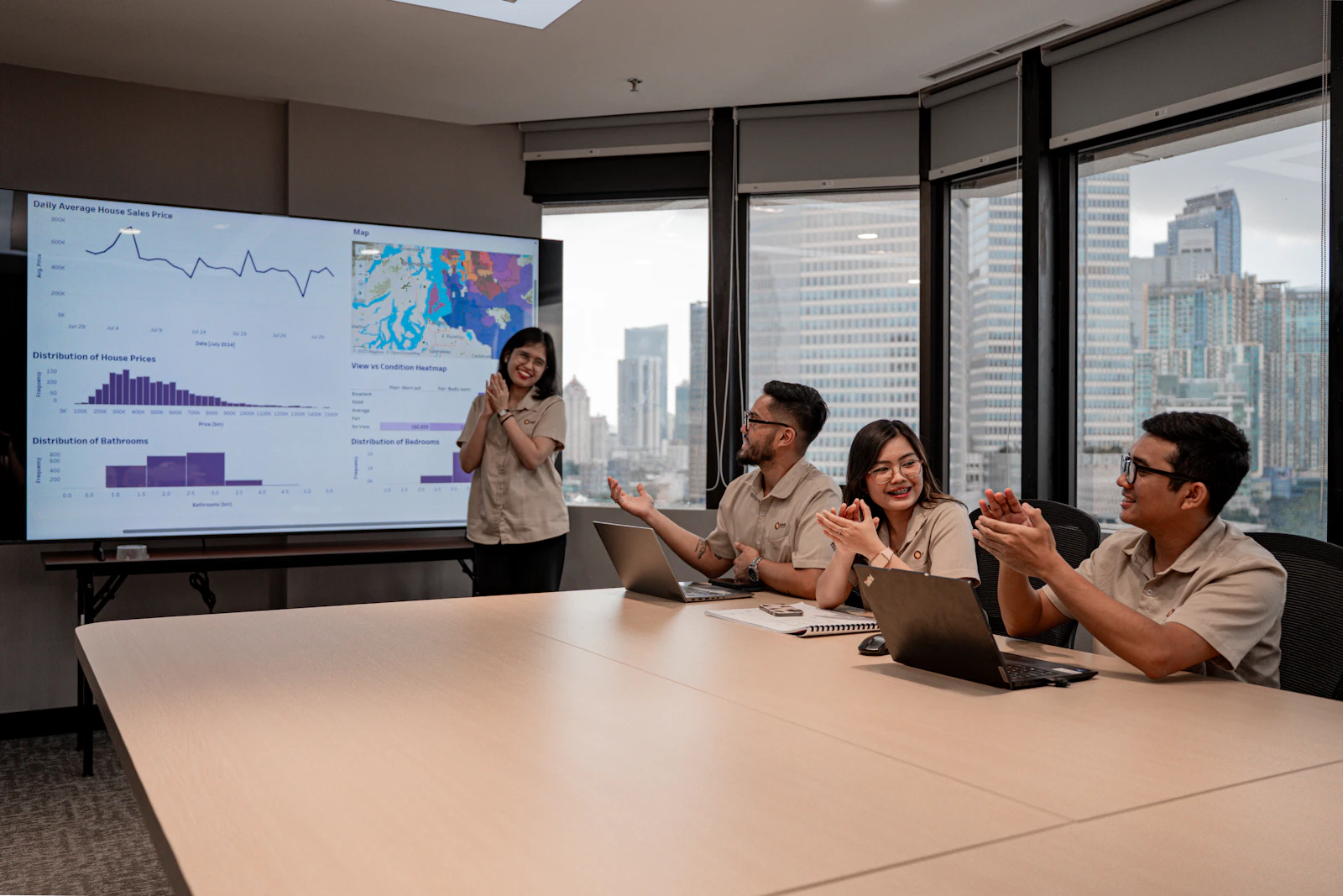 Equipo colaborando durante una presentación de negocios con datos en pantalla.