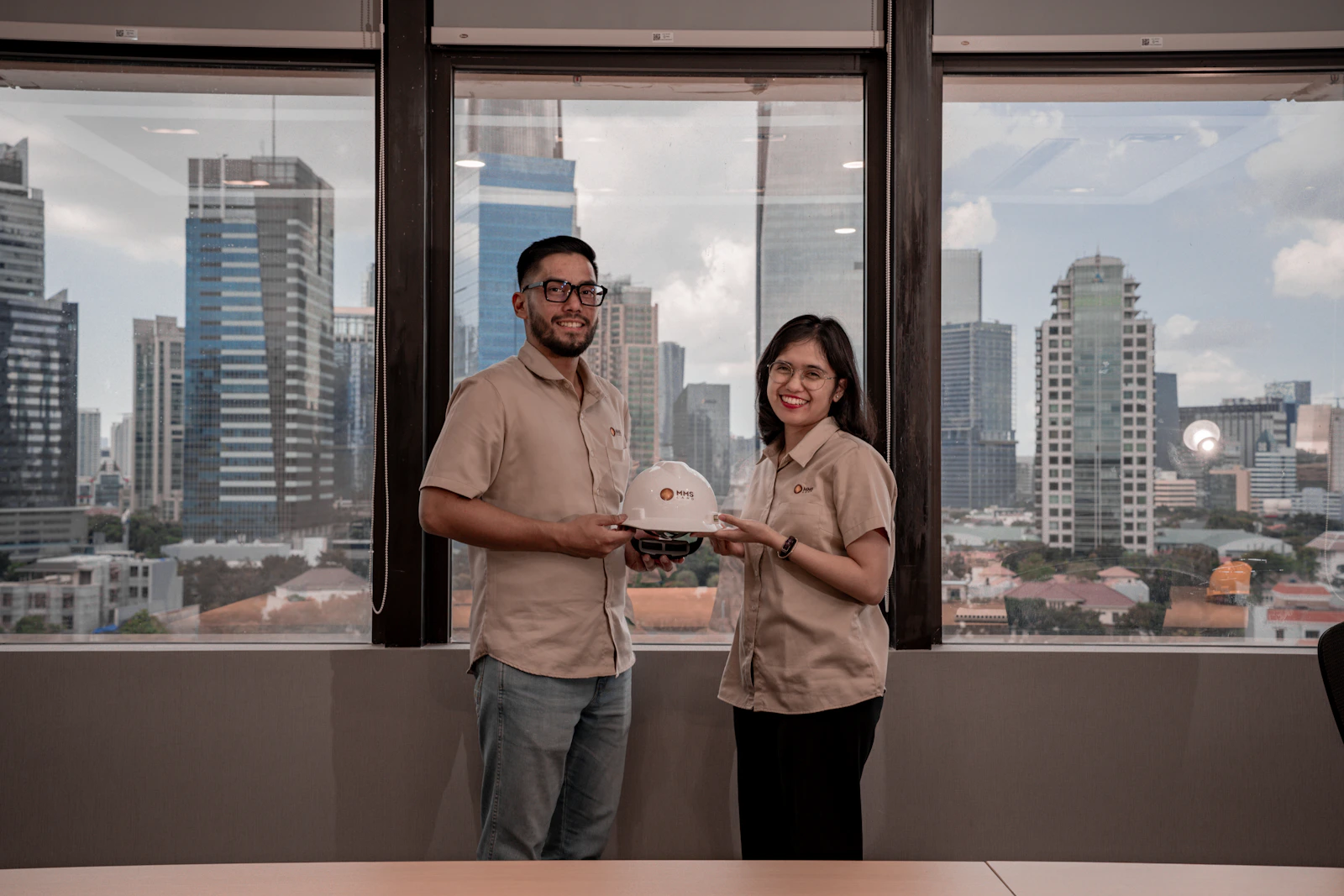 Two construction professionals holding a hard hat while overlooking a city, representing recruiting and career development in the skilled trades.