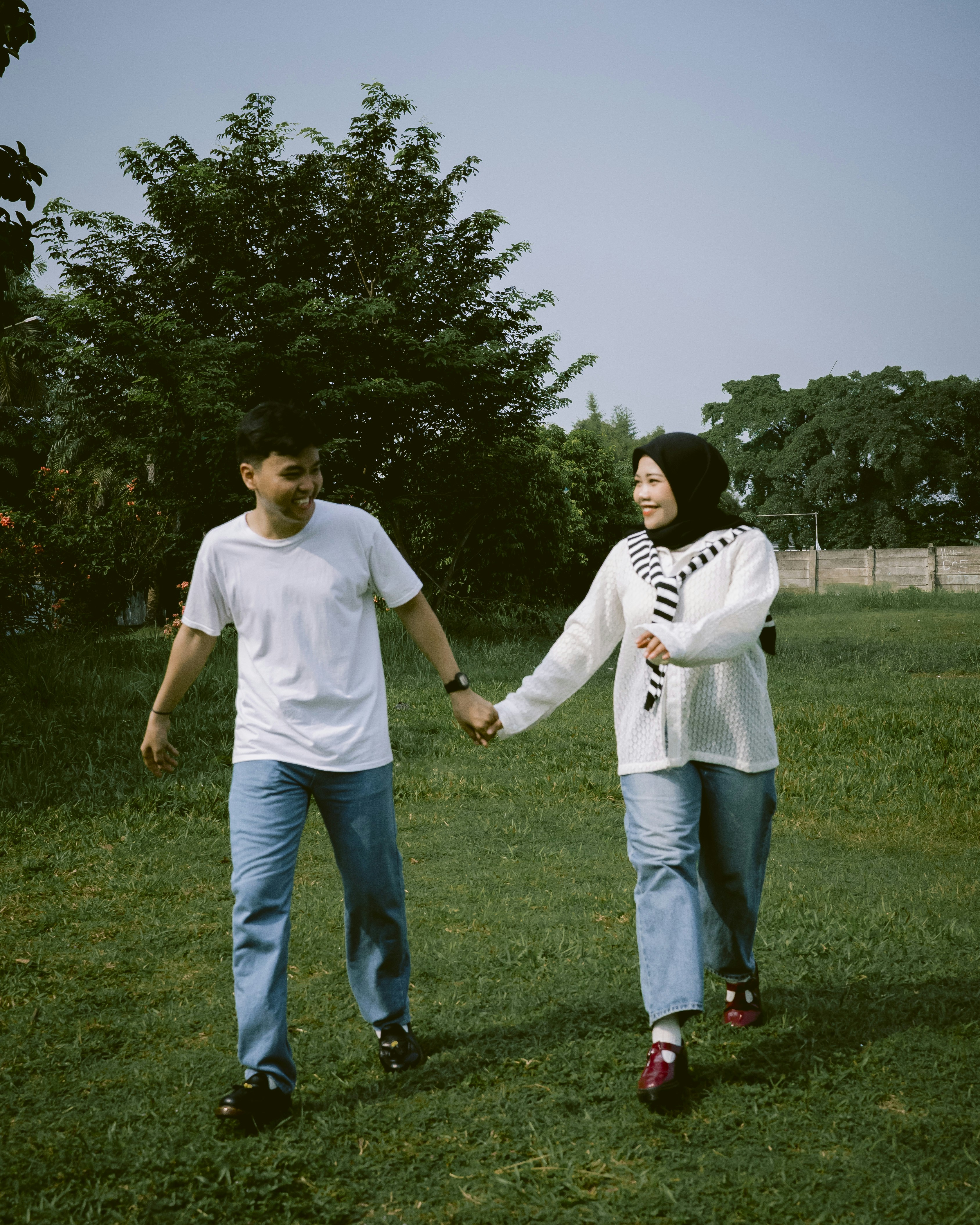Couple holding hands walking in grassy park