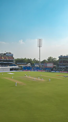Cricket match in progress on a sunny day at stadium.