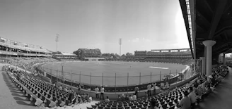 Empty stadium seats with a cricket field in the background.