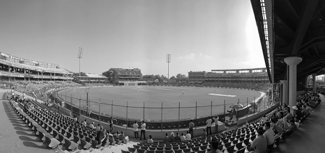 Empty stadium seats with a cricket field in the background.