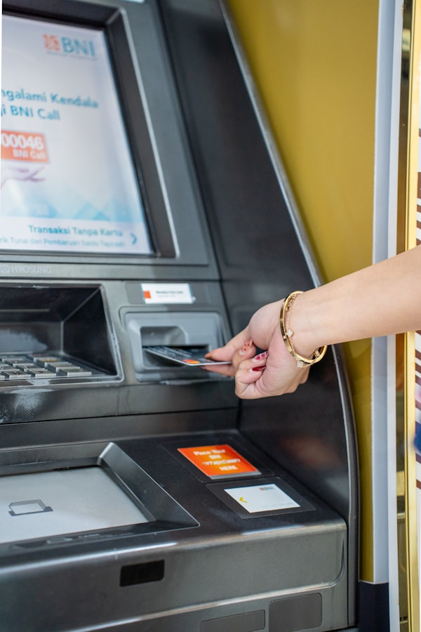 Hand hält eine Bankkarte am Geldautomaten