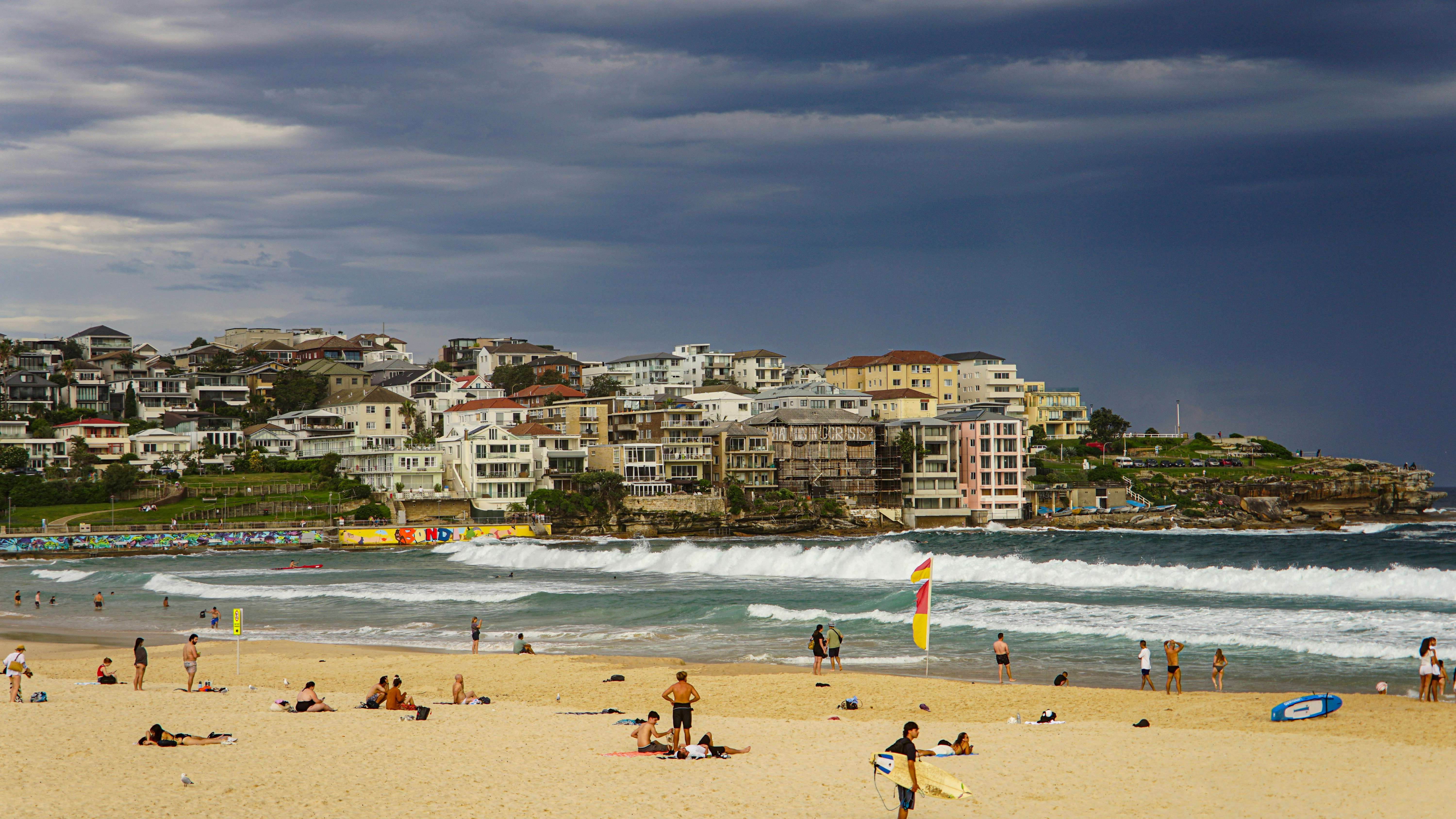 People relaxing on a sandy beach with buildings overlooking