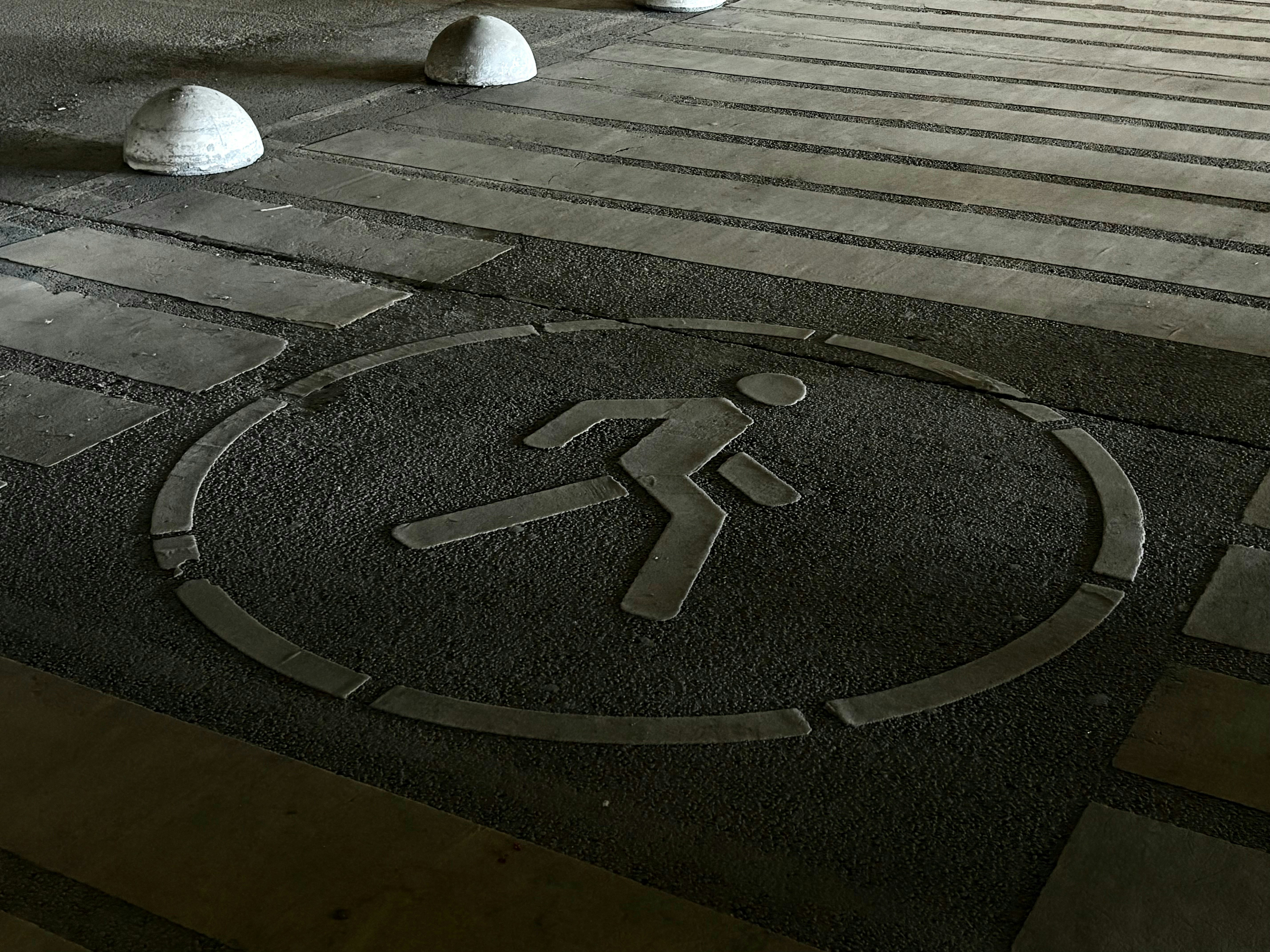 보도에 있는 달리는 사람 심볼과 배경에 볼라드가 있습니다