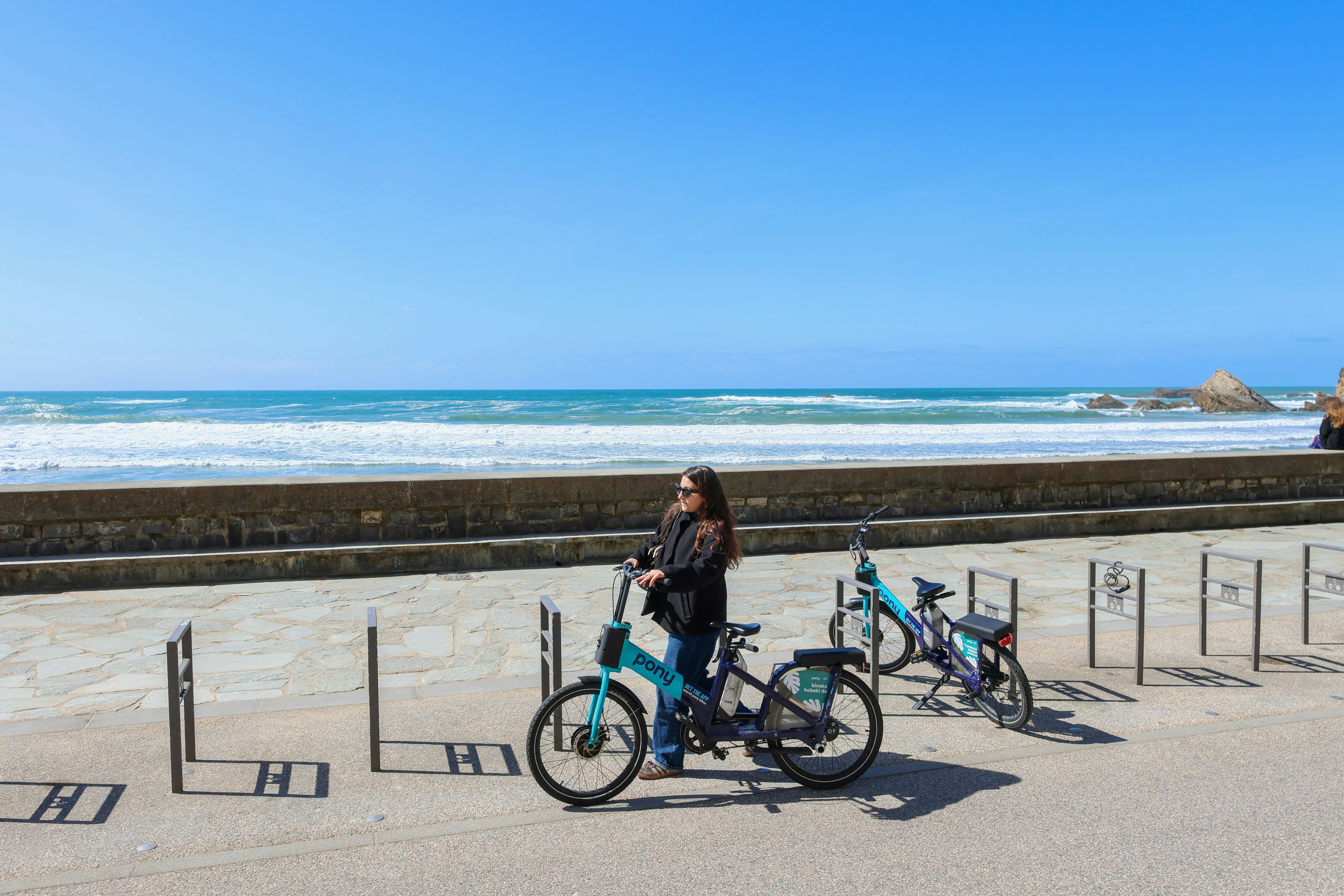Frau mit Fahrrädern am Meer an einem sonnigen Tag