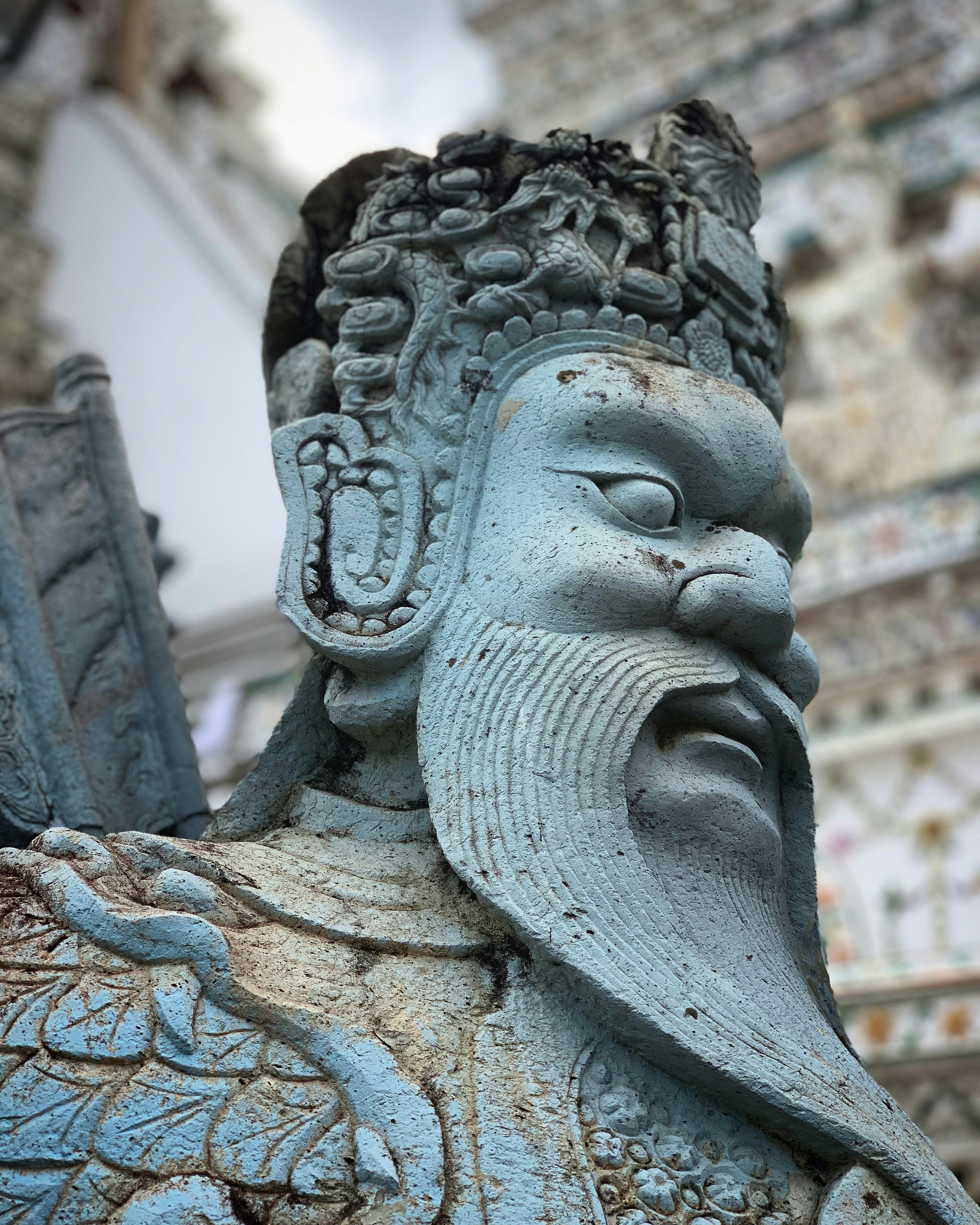 Estatua de piedra del guardián con tocado y barba ornamentados