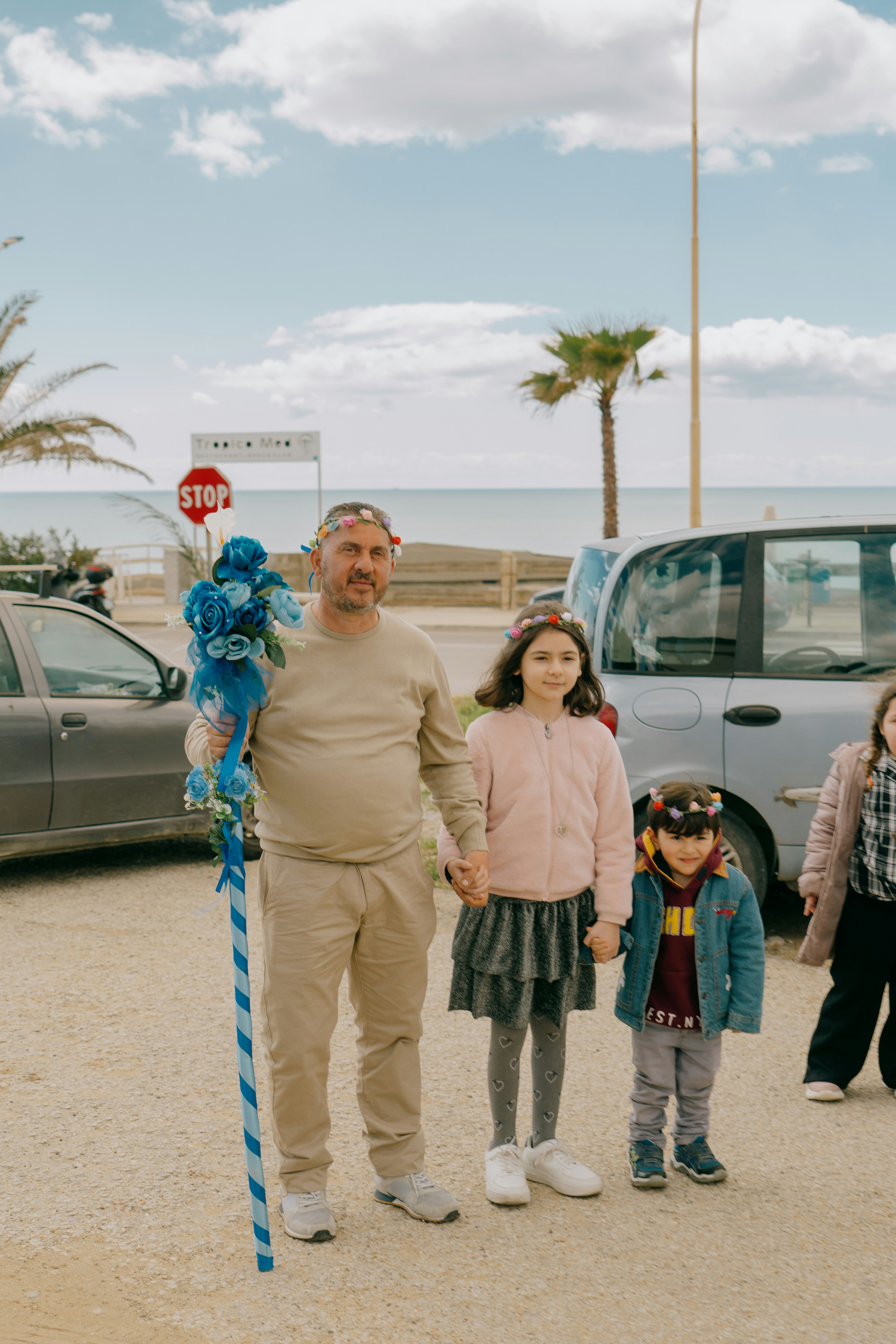 Man holds decorated staff with two children
