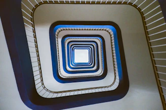 Looking down a modern spiral staircase with blue accents.